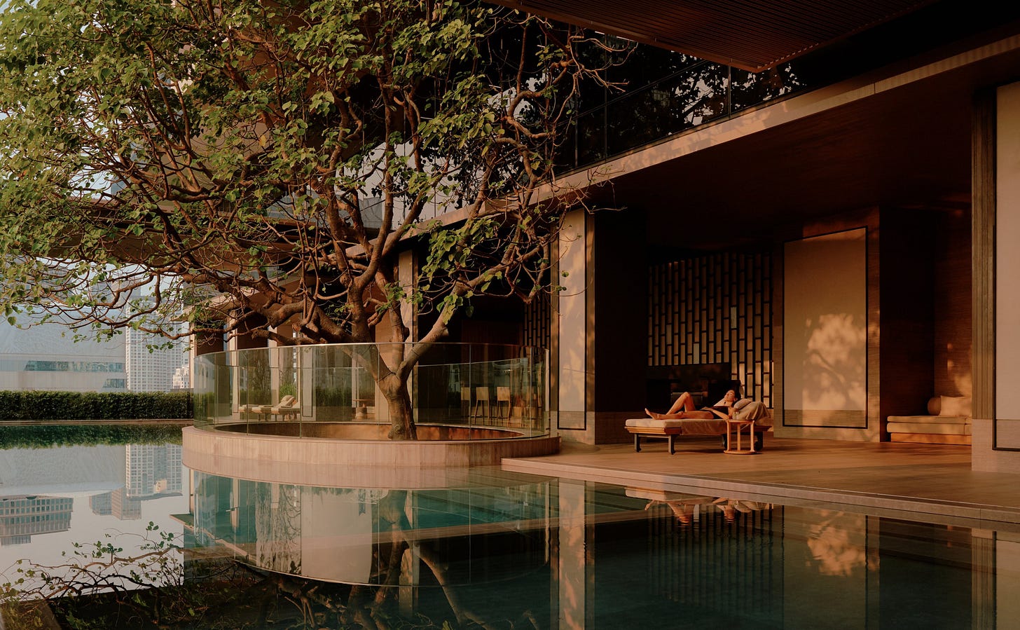 Wellness swimming pool at Aman Nai Lert Bangkok, with wooden platform beside calm water and traditional Thai architecture.