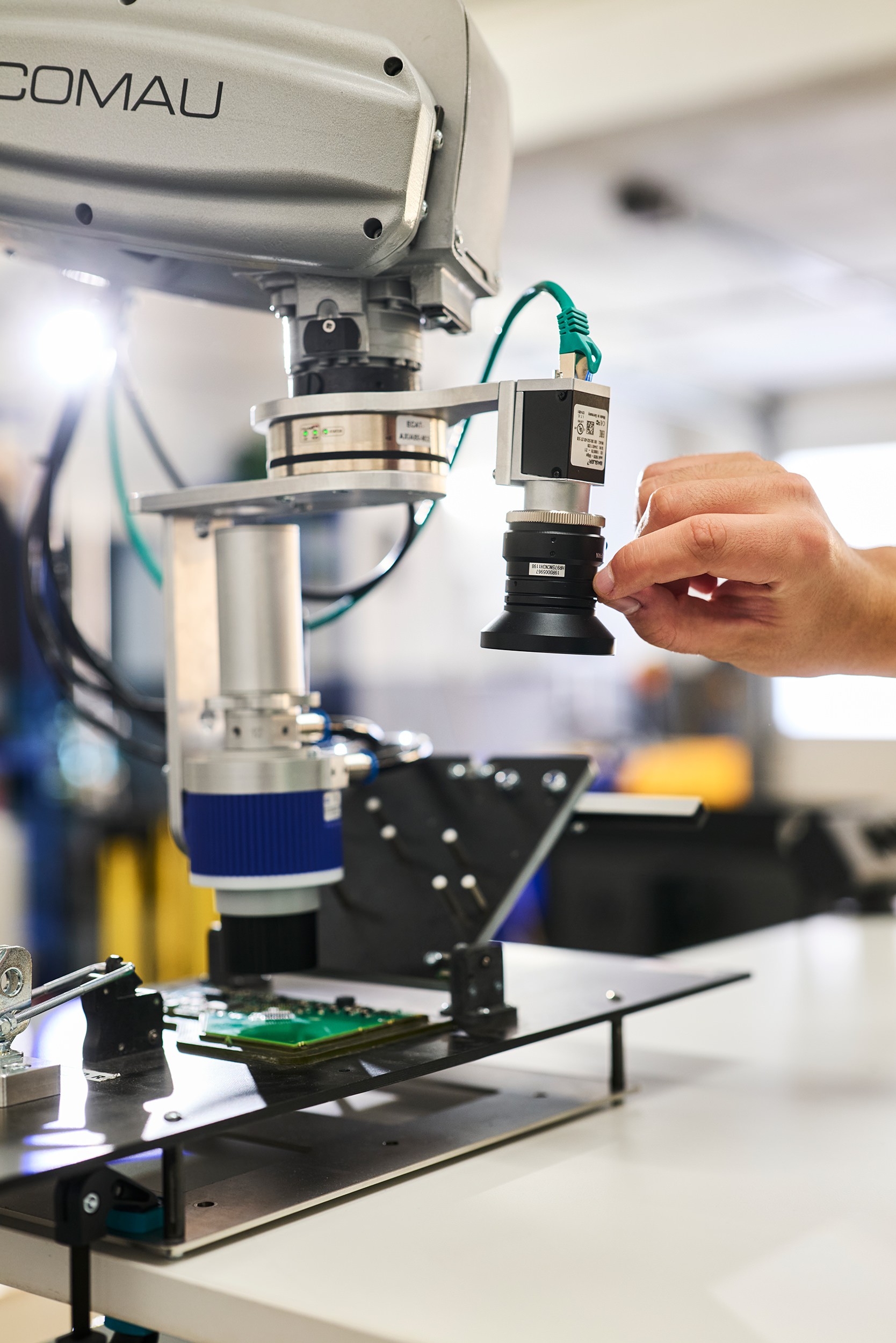 Close-up photo, hand adjusting lens on robot, industrial photography