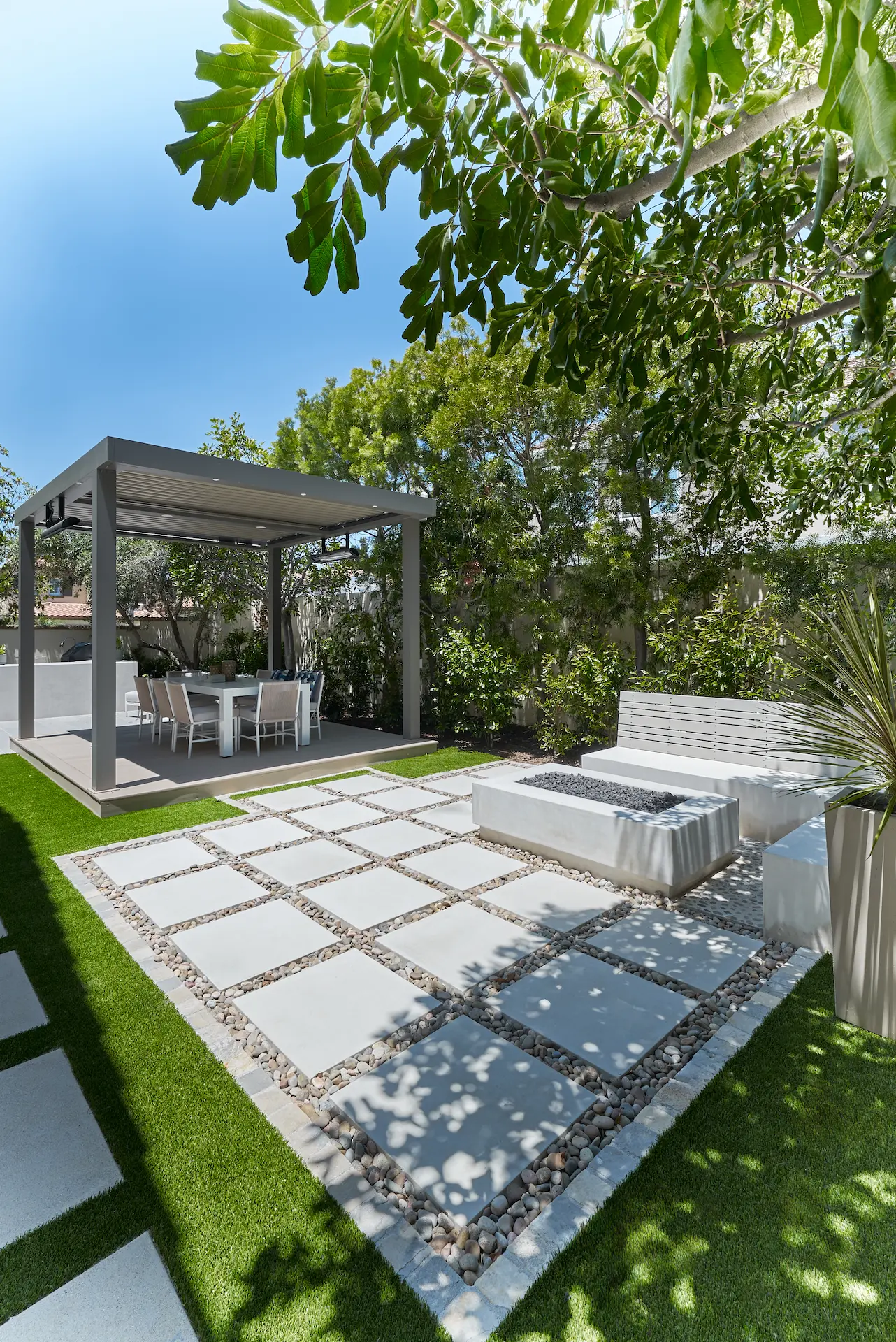 Wide portrait view of the hardscape, showcasing the firepit seating area and covered patio in the Irvine Contemporary Coastal Remodel.