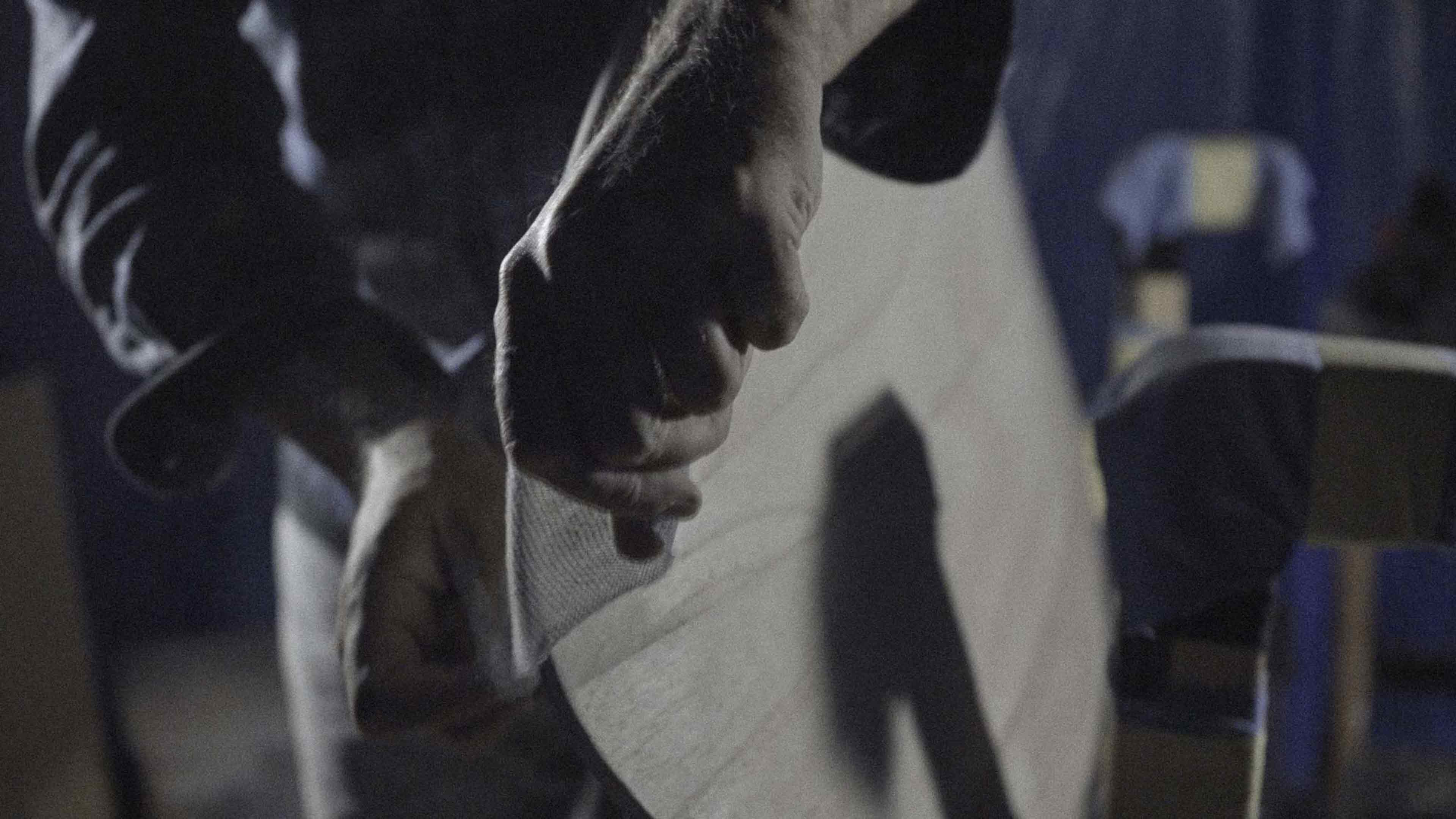 Surfboard shaper sanding wooden surfboard rail