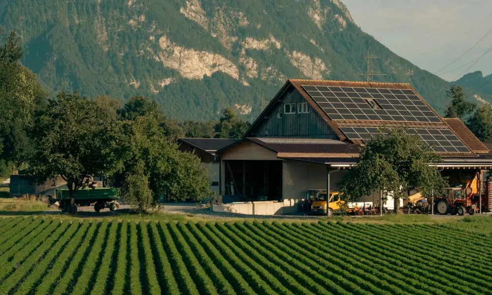 Bauernhaus mit Traktoren vor grüner Kultur im Berner Oberland.