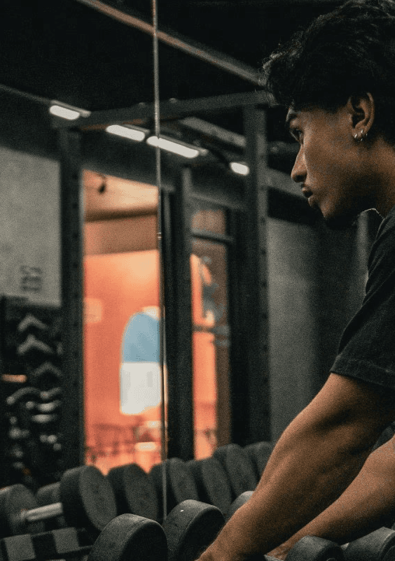 Two individuals are working out in a gym, focusing on dumbbells and strength training equipment.