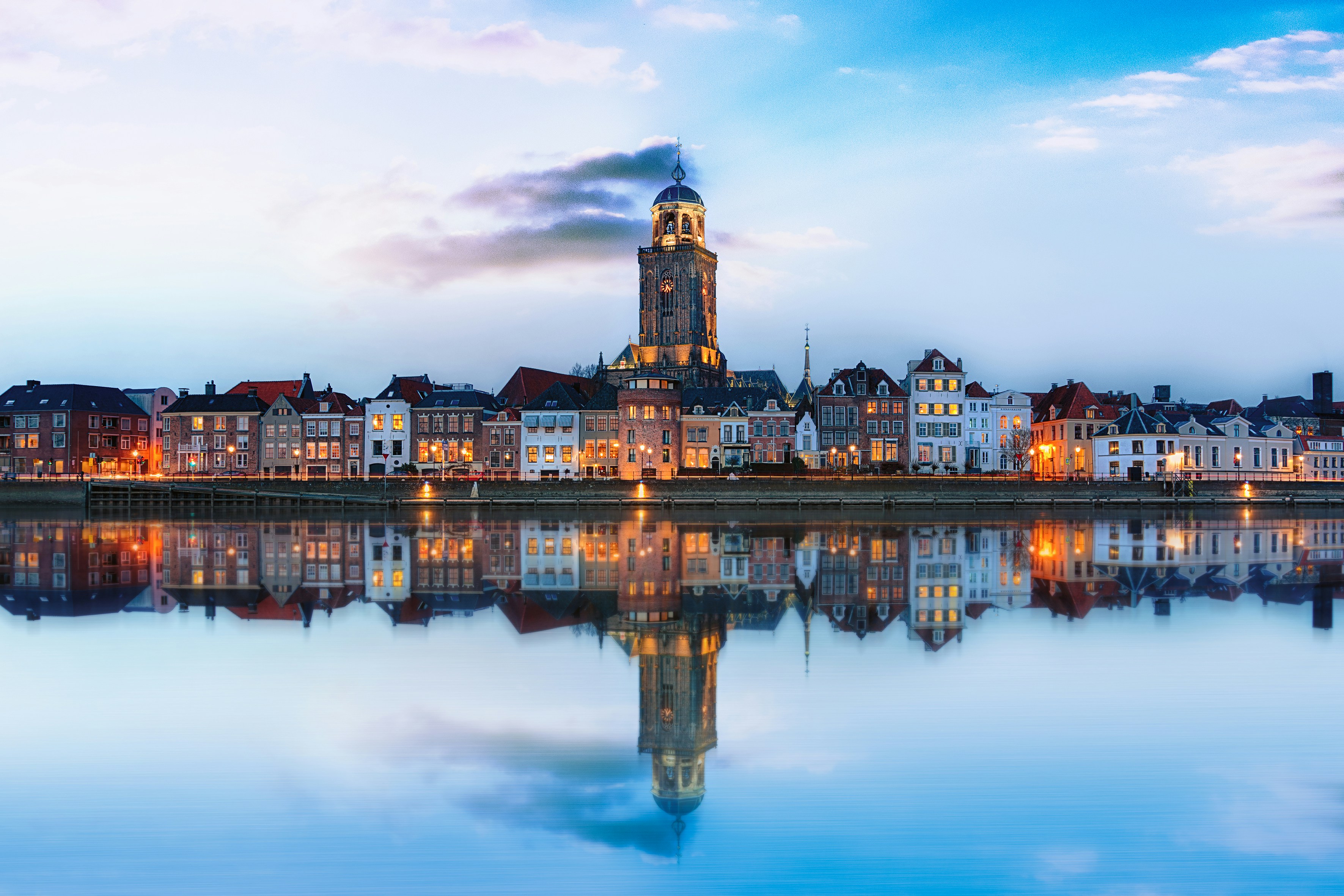 Avondfoto van de skyline van Deventer aan de IJssel met de Lebuïnuskerk en spiegeling in het water, gebruikt voor de lokale pagina van Verhuisteam Blauw