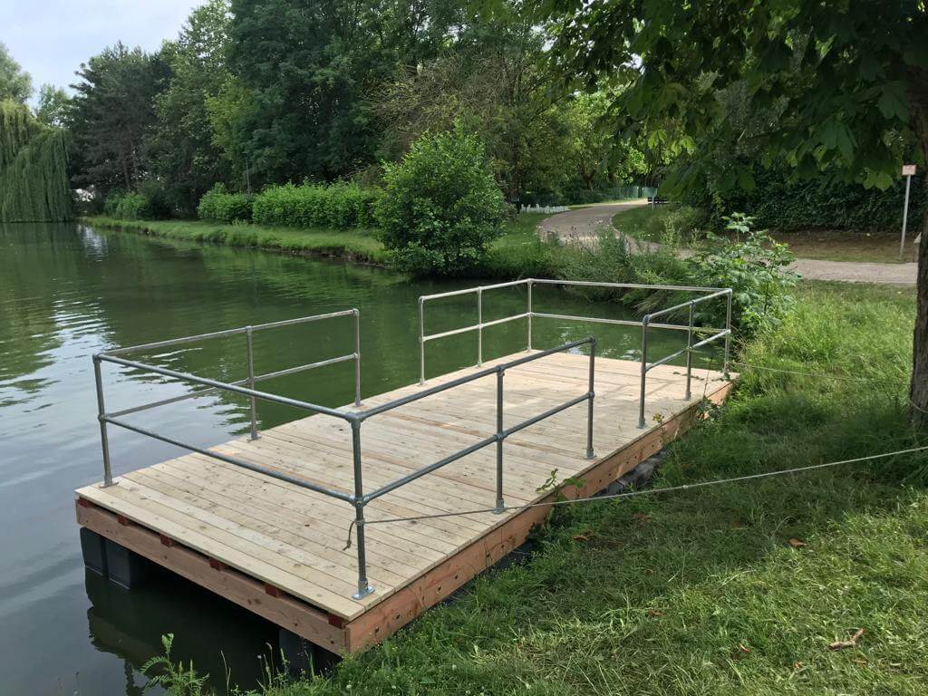 Smiling young man with short hair poses against a dark background, wearing a green button-up shirt.