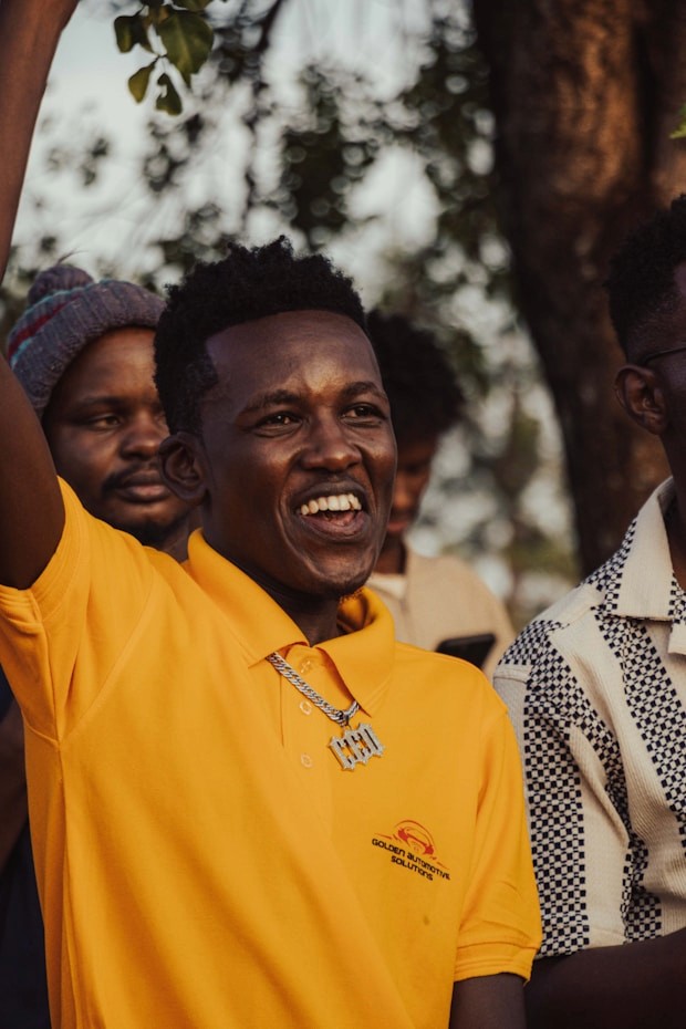 Man in yellow shirt with arms raised, smiling