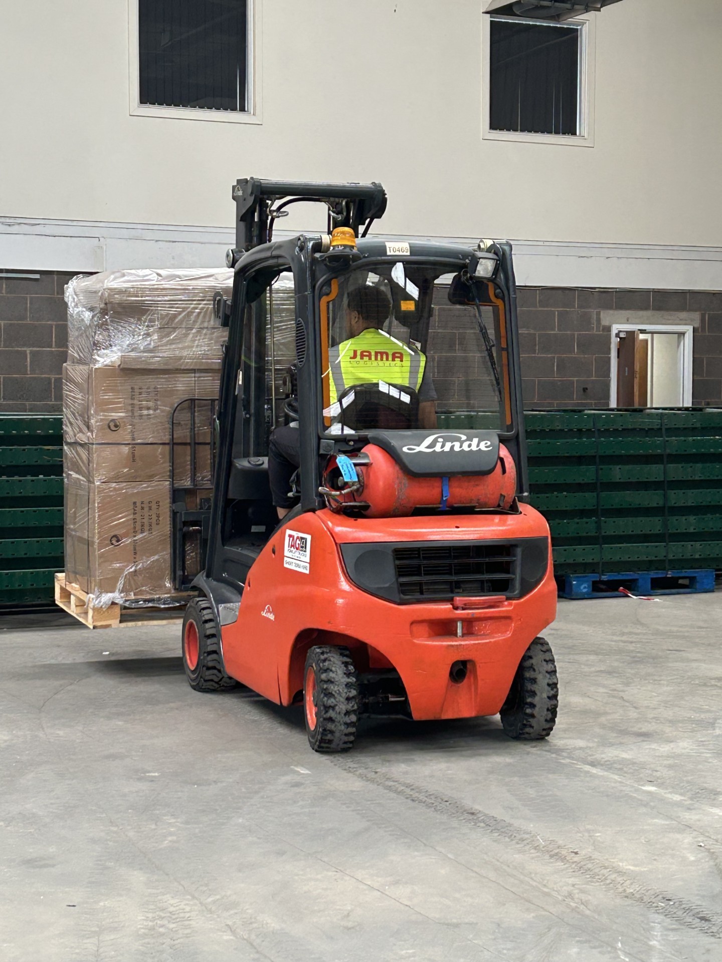 image of a person wearing jama logistics branded high vis driving a forklift carrying a pallet