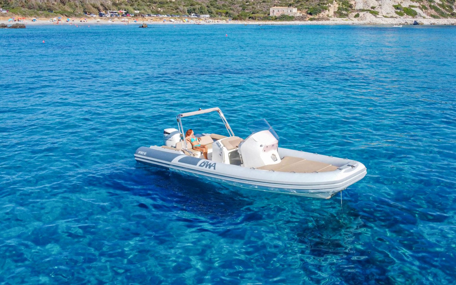 Boat on the Gulf of Cagliari during a guided tour, with clear blue water and distant shoreline.