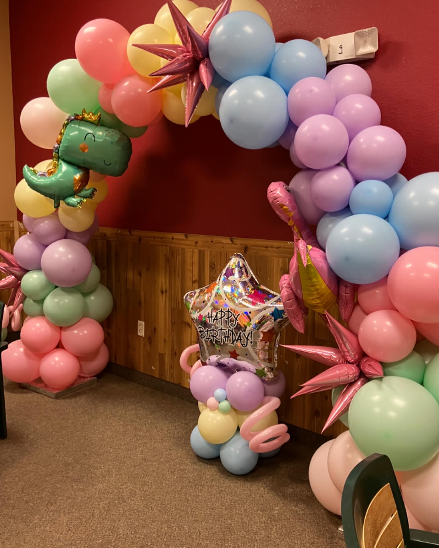 Pastel balloon arch with a mix of pink, blue, green, and yellow balloons and a unicorn balloon centerpiece created by Be Bold Balloons