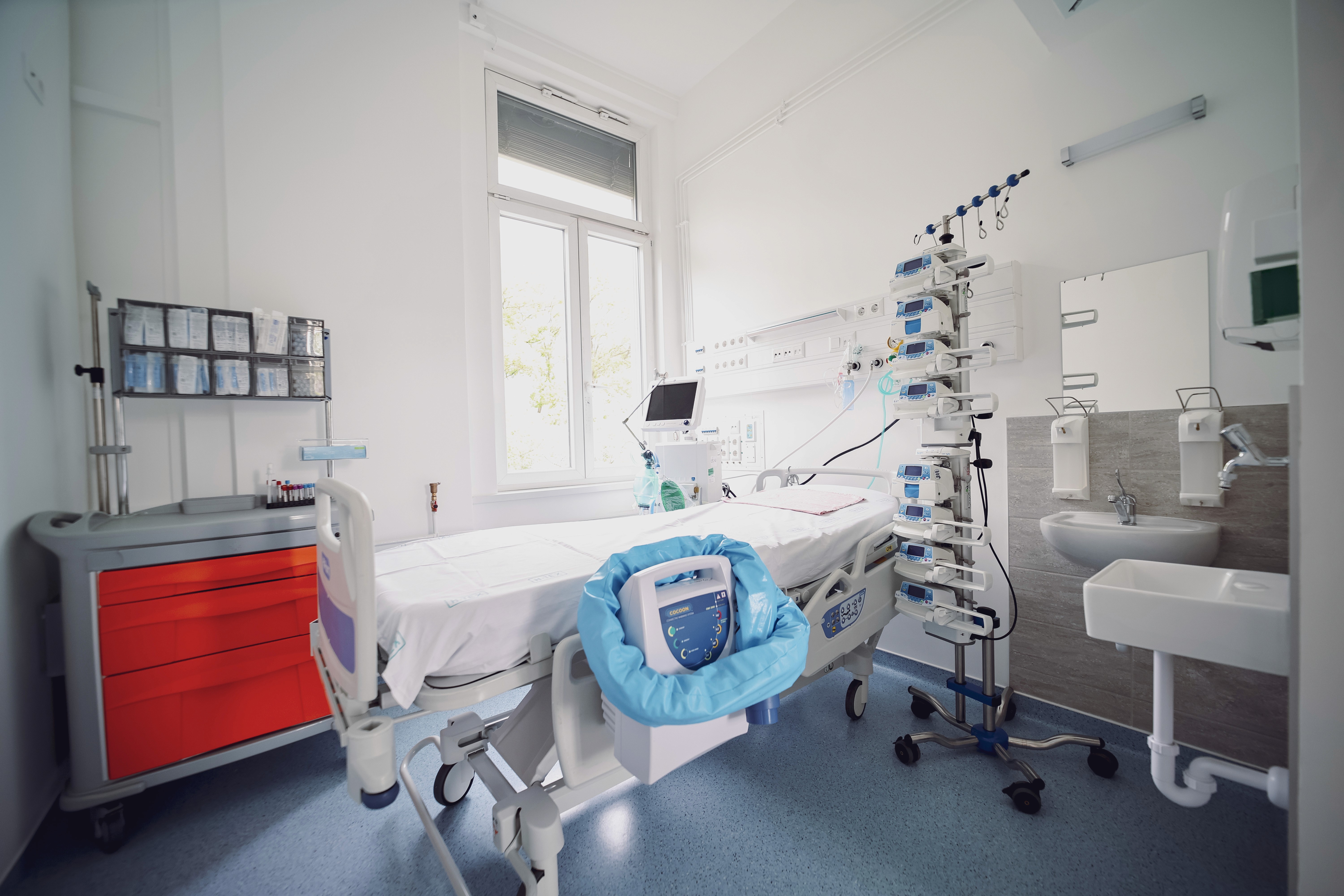 A kórház egyik jól felszerelt szobája látható, ággyal, mosdóval, szekrényekkel.