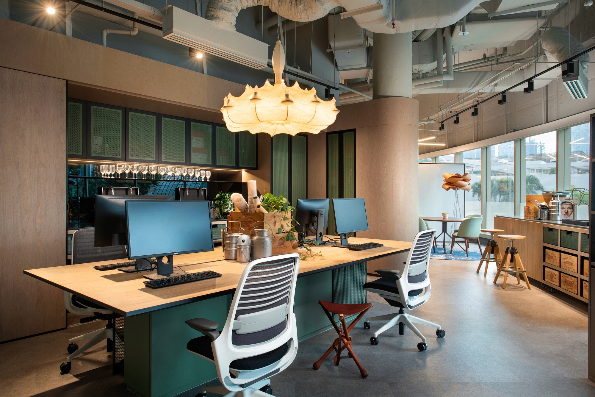 Modern office space featuring desks with computers, ergonomic chairs, and stylish lighting. Bright and inviting atmosphere.