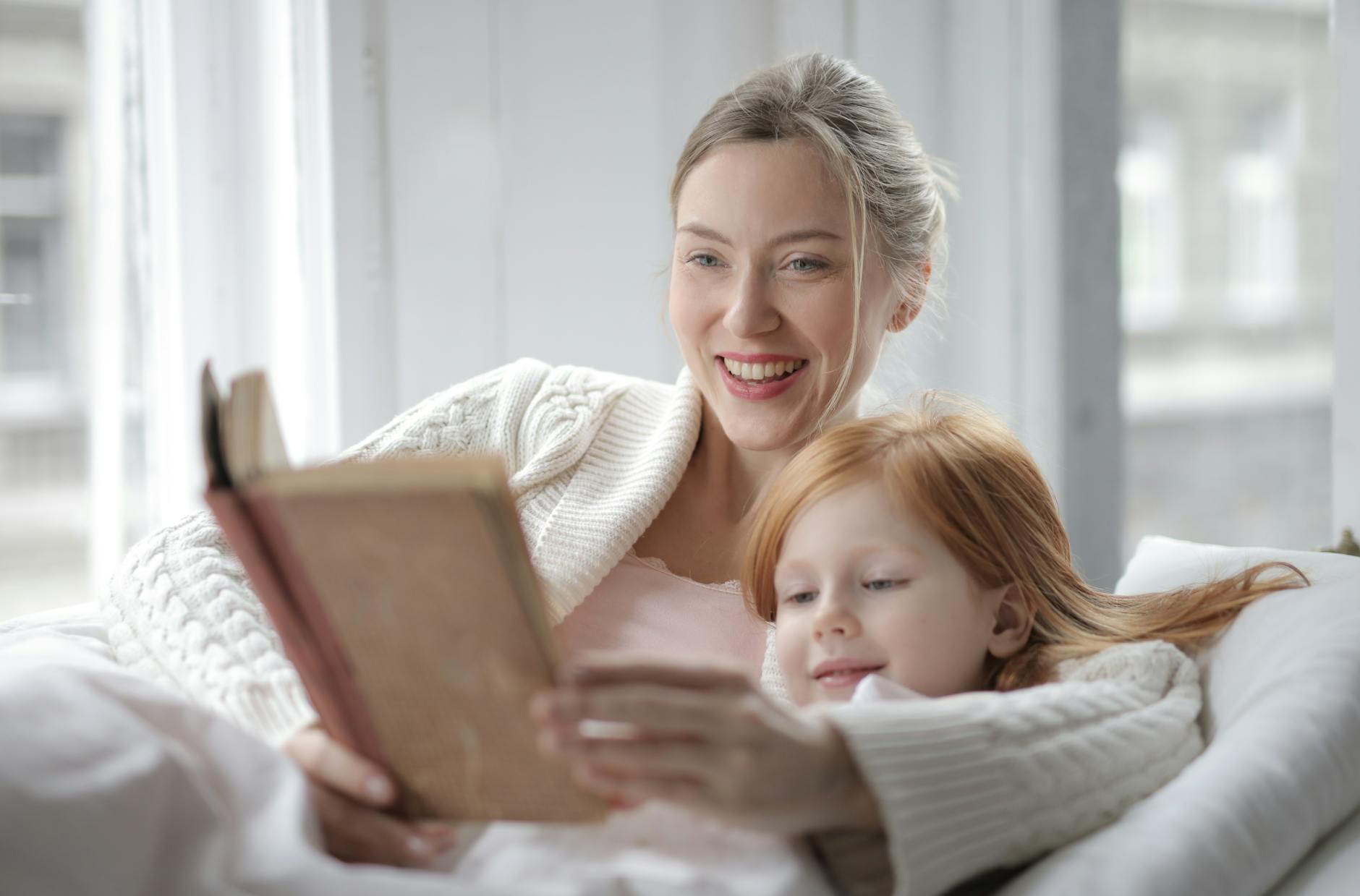 Two elementary students sitting on a beanbag chair laughing while sharing a humorous illustrated storybook.