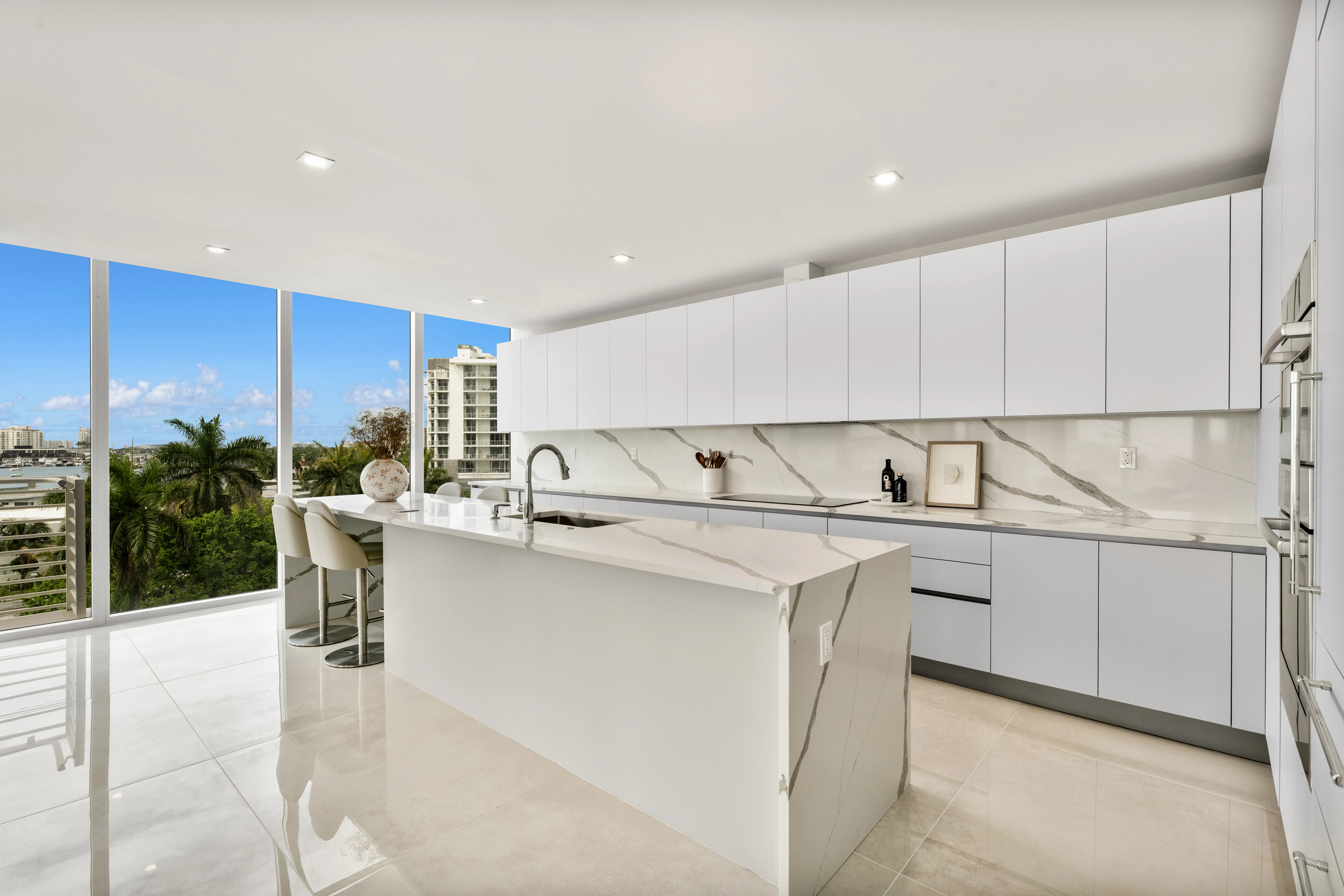 Stylish kitchen and living room area showcasing a beautiful ocean view through large glass windows.