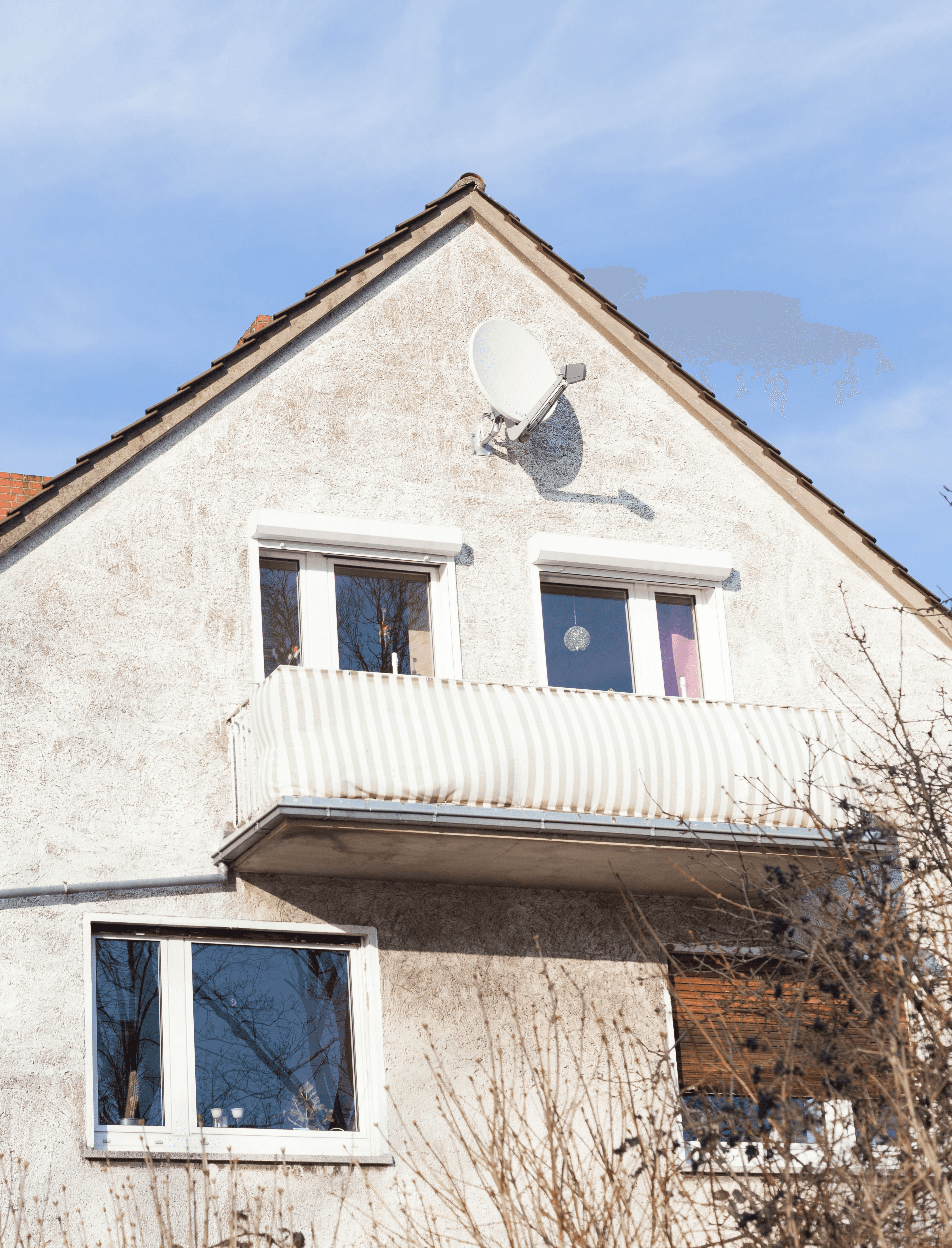 A smiling young man with crossed arms, wearing a plaid shirt and white t-shirt, poses against a dark background.