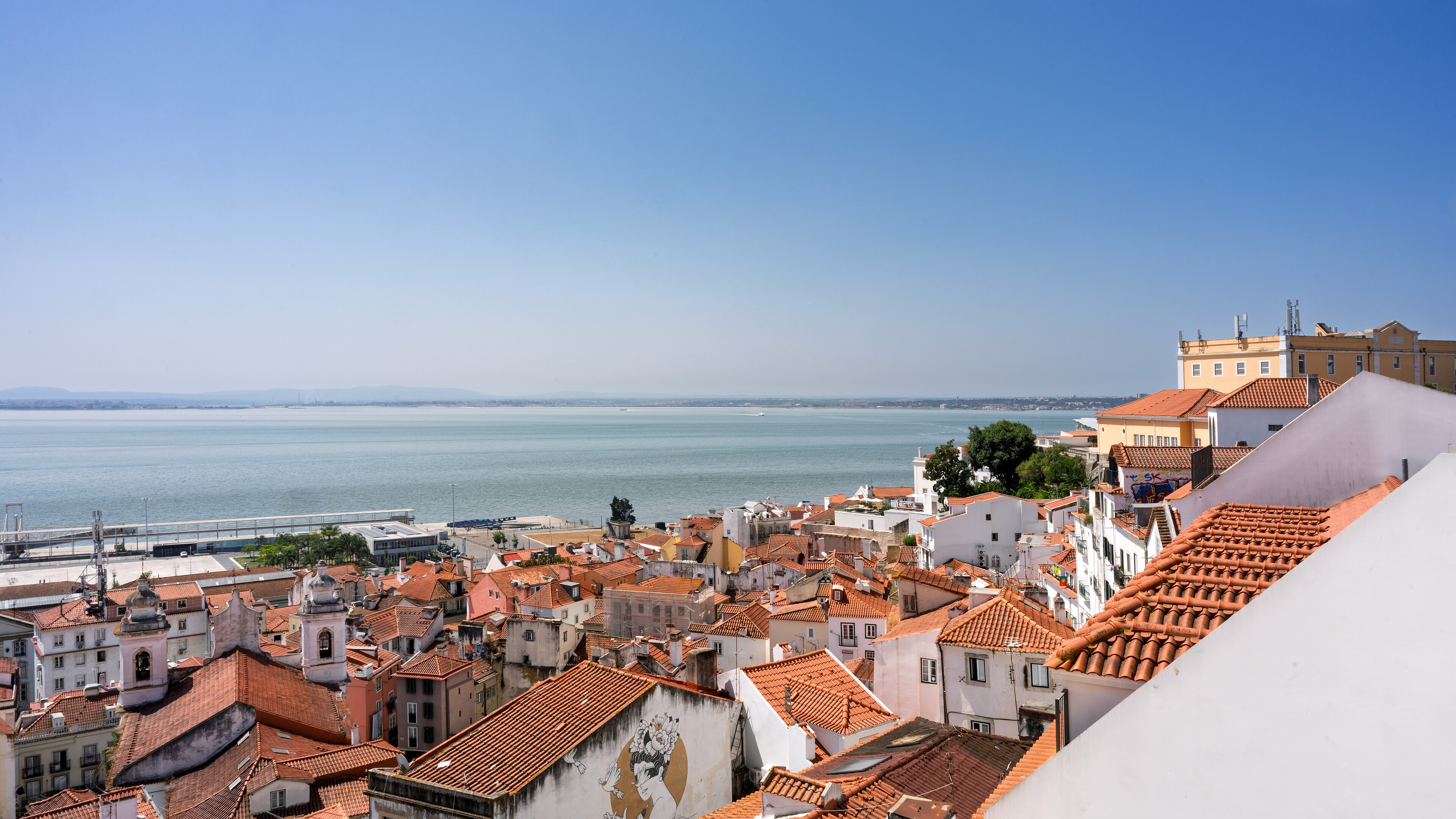 Terracotta rooftops of Lisbon’s Alfama neighborhood overlooking the Tagus River