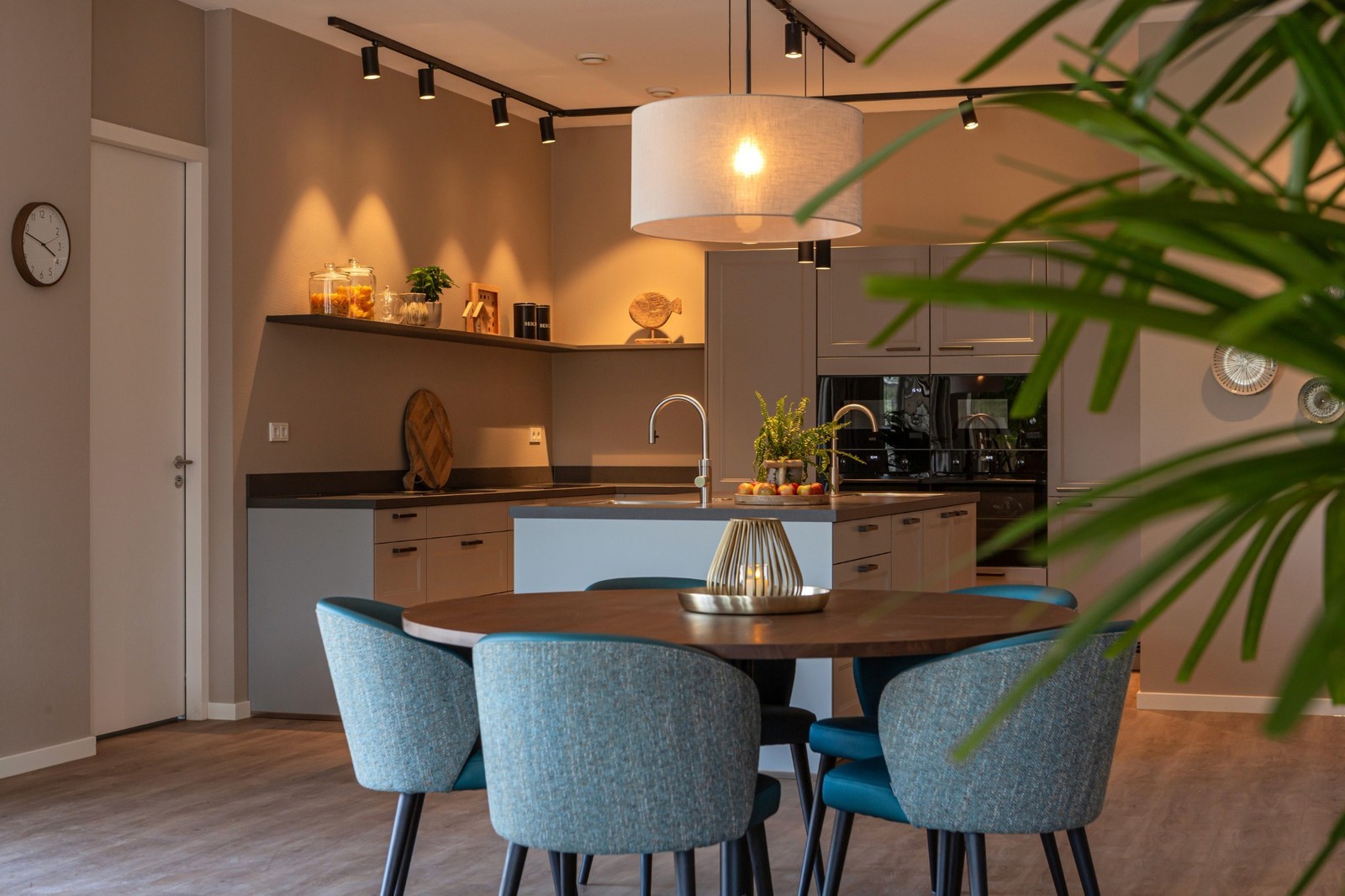 woonkeuken grijs met ronde eettafel en blauwe stoelen 