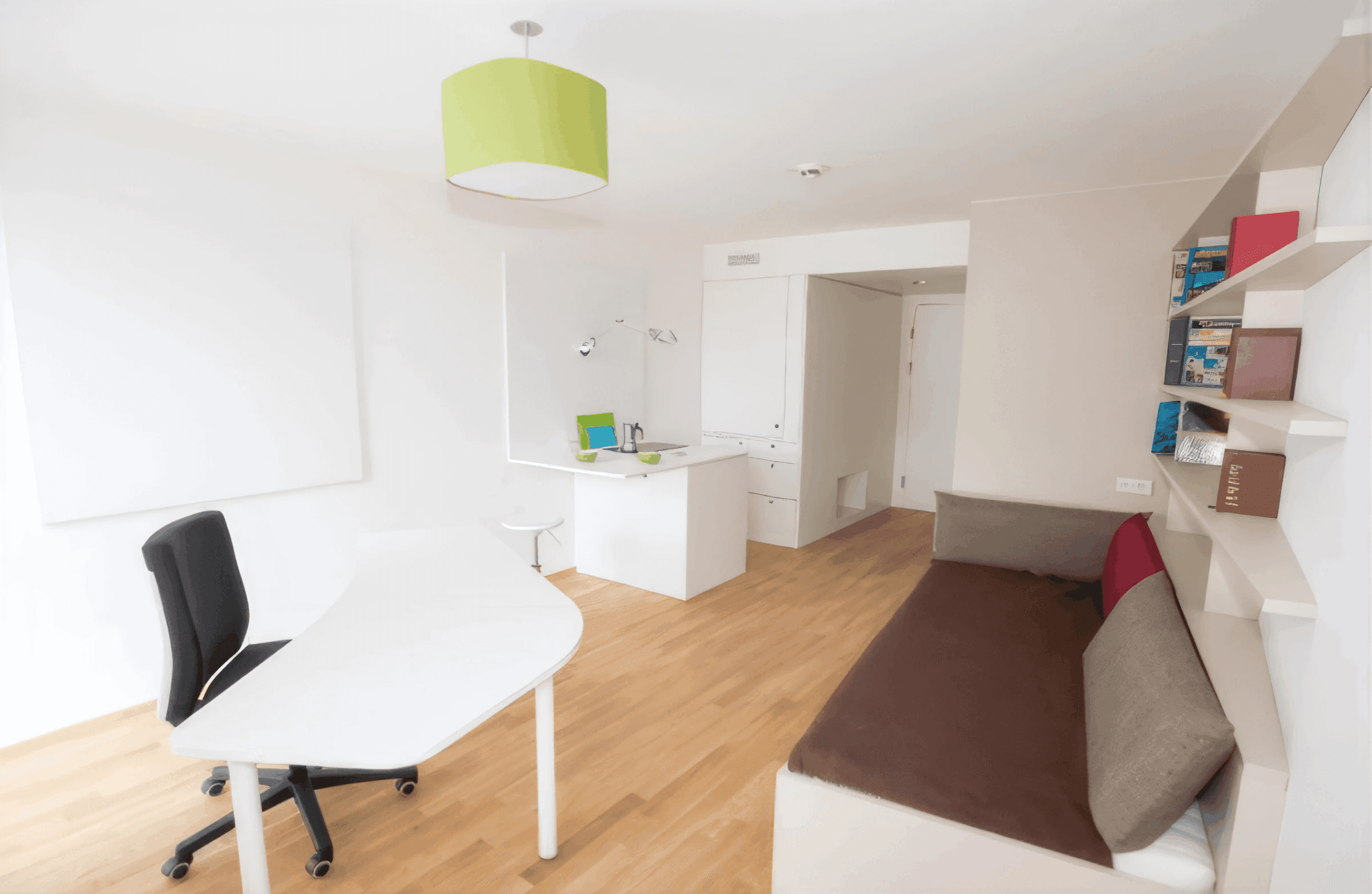 MW Interior - Helles Studentenapartment mit weißem Schreibtisch, schwarzem Bürostuhl, integrierter Küchenzeile, Sofa und grüner Pendelleuchte auf Holzparkett" Beschreibung: Kompakt und durchdacht eingerichtetes Studentenzimmer mit weißem Schwenktisch, integrierter Miniküche, wandseitigem Bücherregal und einem Sofa – alles auf kleinstem Raum funktional vereint.