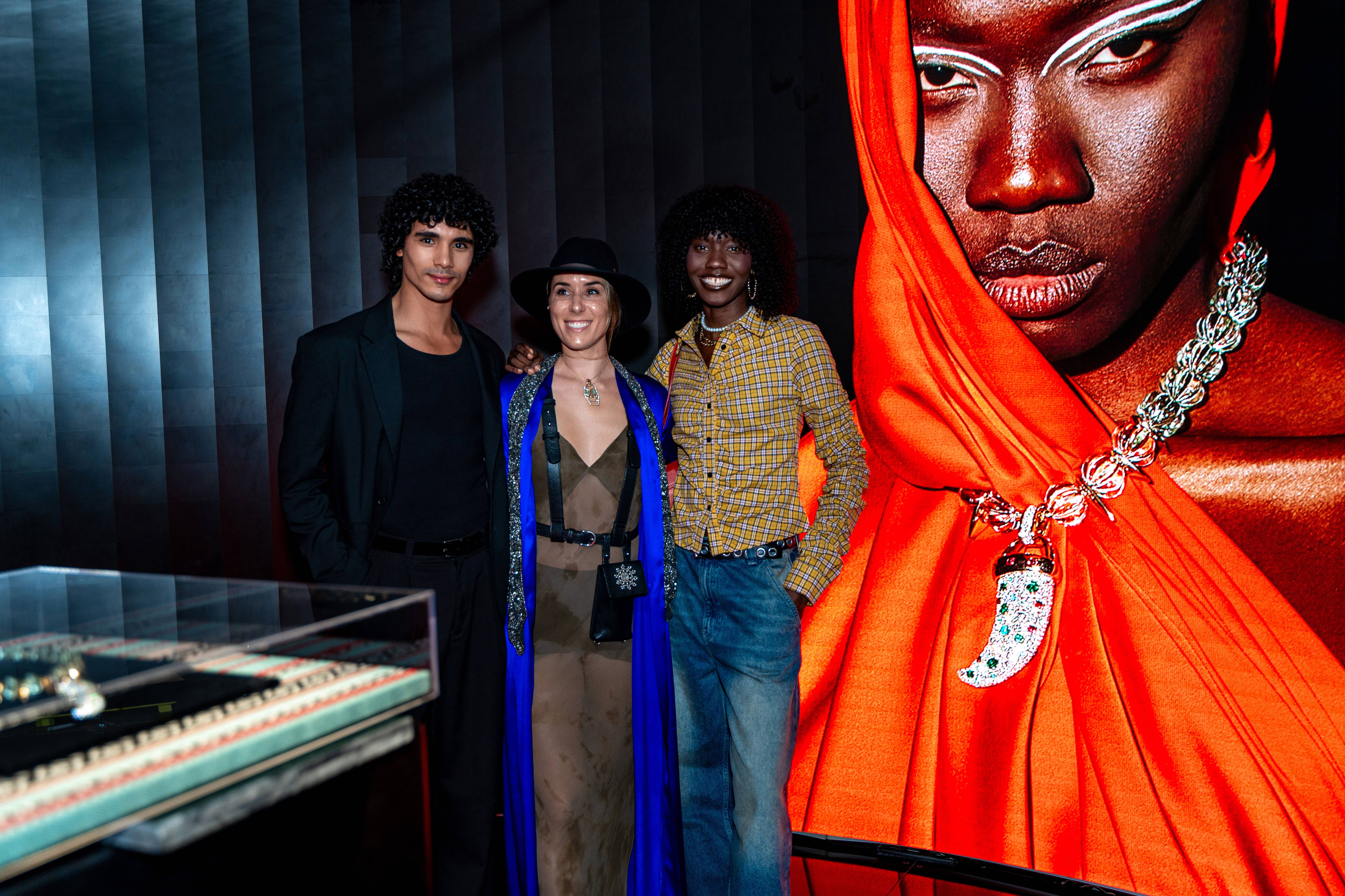 Three models standing in a wheat field, wearing beige suits.