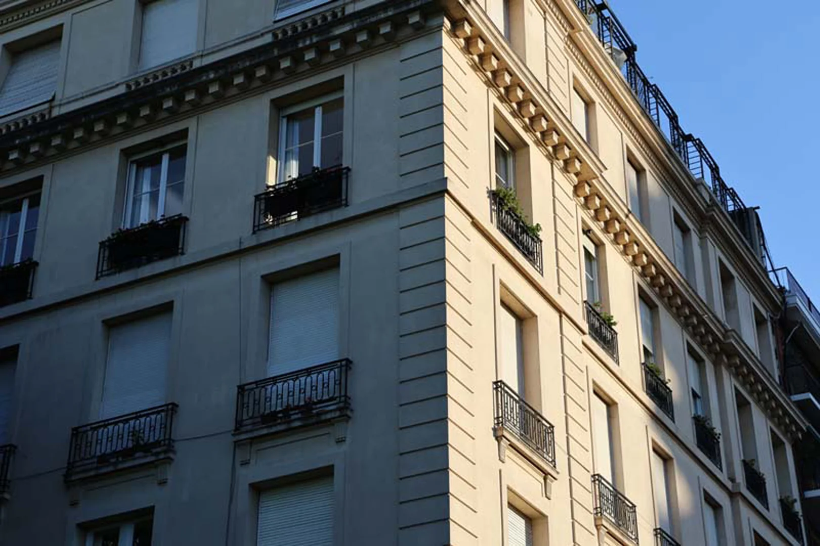 Fachada clásica de esquina de un edificio residencial en Recoleta con balcones de hierro forjado bajo luz de tarde cálida.