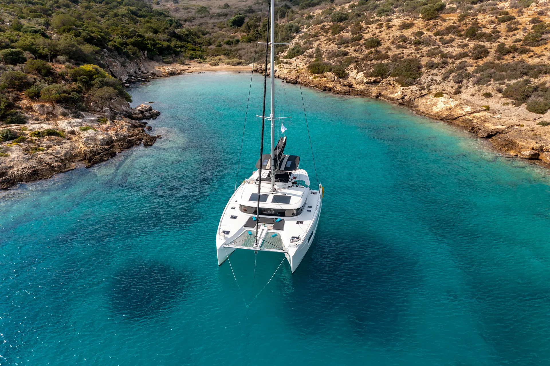 White Rock 36 speedboat with captain at helm cruising calm blue waters near Paros coastline with hills in background.
