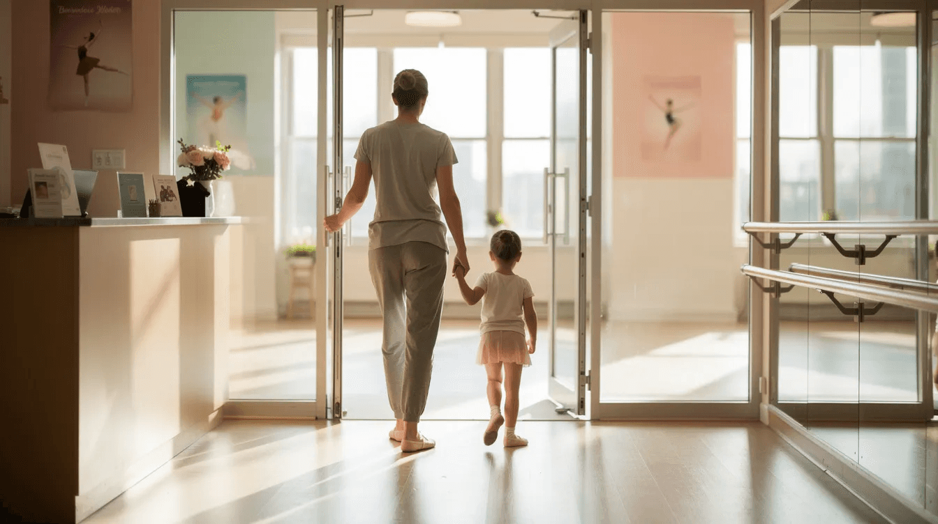 A parent and a young child are happily walking through the doors of a bright and welcoming dance studio, ready to engage in a class designed to enhance their abilities. This inviting atmosphere encourages parents to book trials through class management software with just a few clicks, ensuring an easy and hassle-free scheduling process.