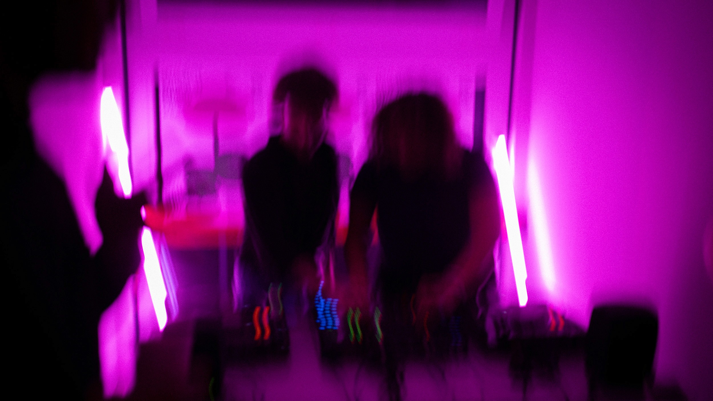 An expressive, motion-blurred photograph of the studio opening party, drenched in neon pink light. This abstract shot emphasizes the high-energy, dynamic nature of the studio’s culture and the immersive environment of their new office launch.