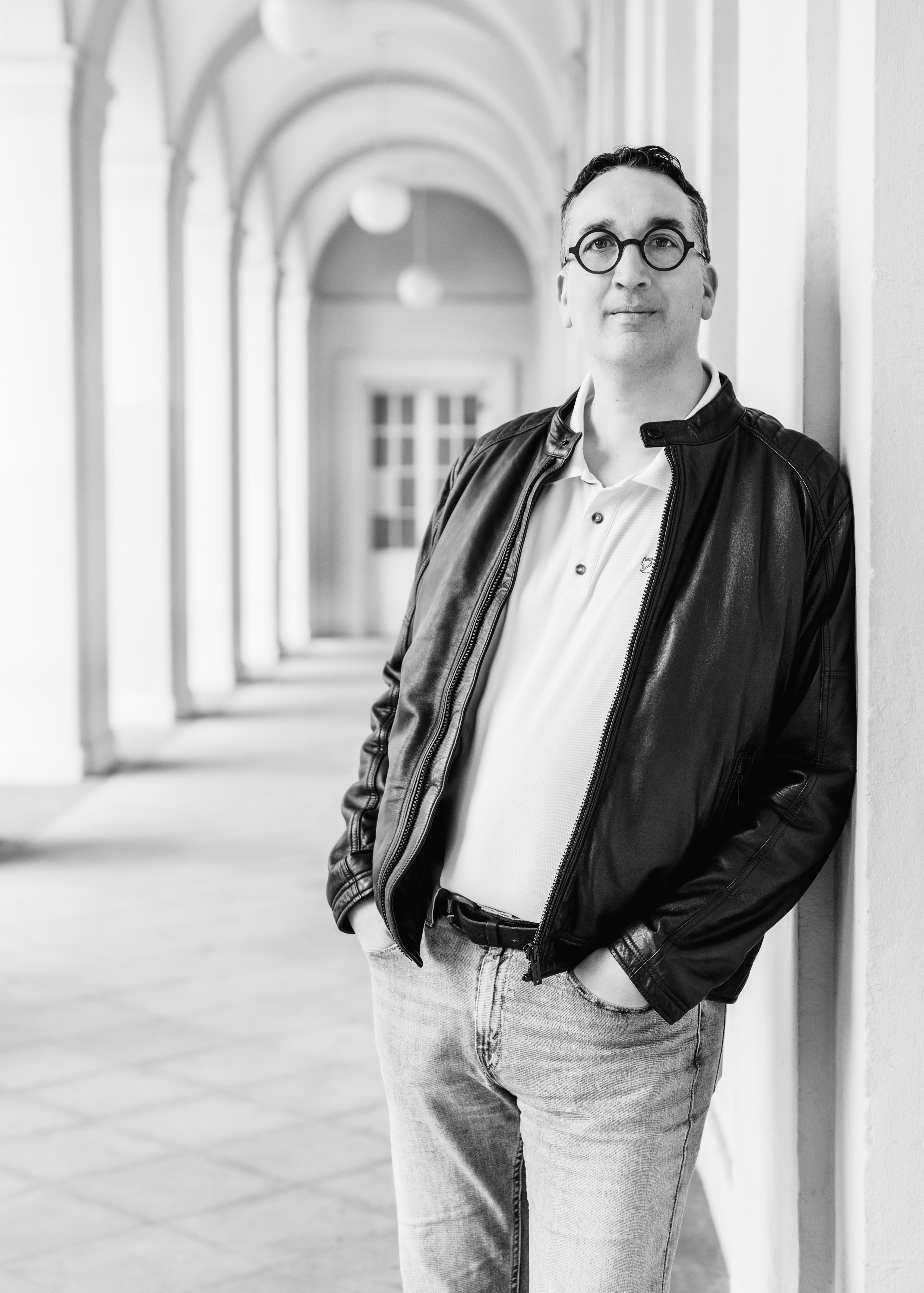 Bernd Winkhaus steht mit Brille und schwarzem Jackett in einer lässigen Pose in Arcaden.