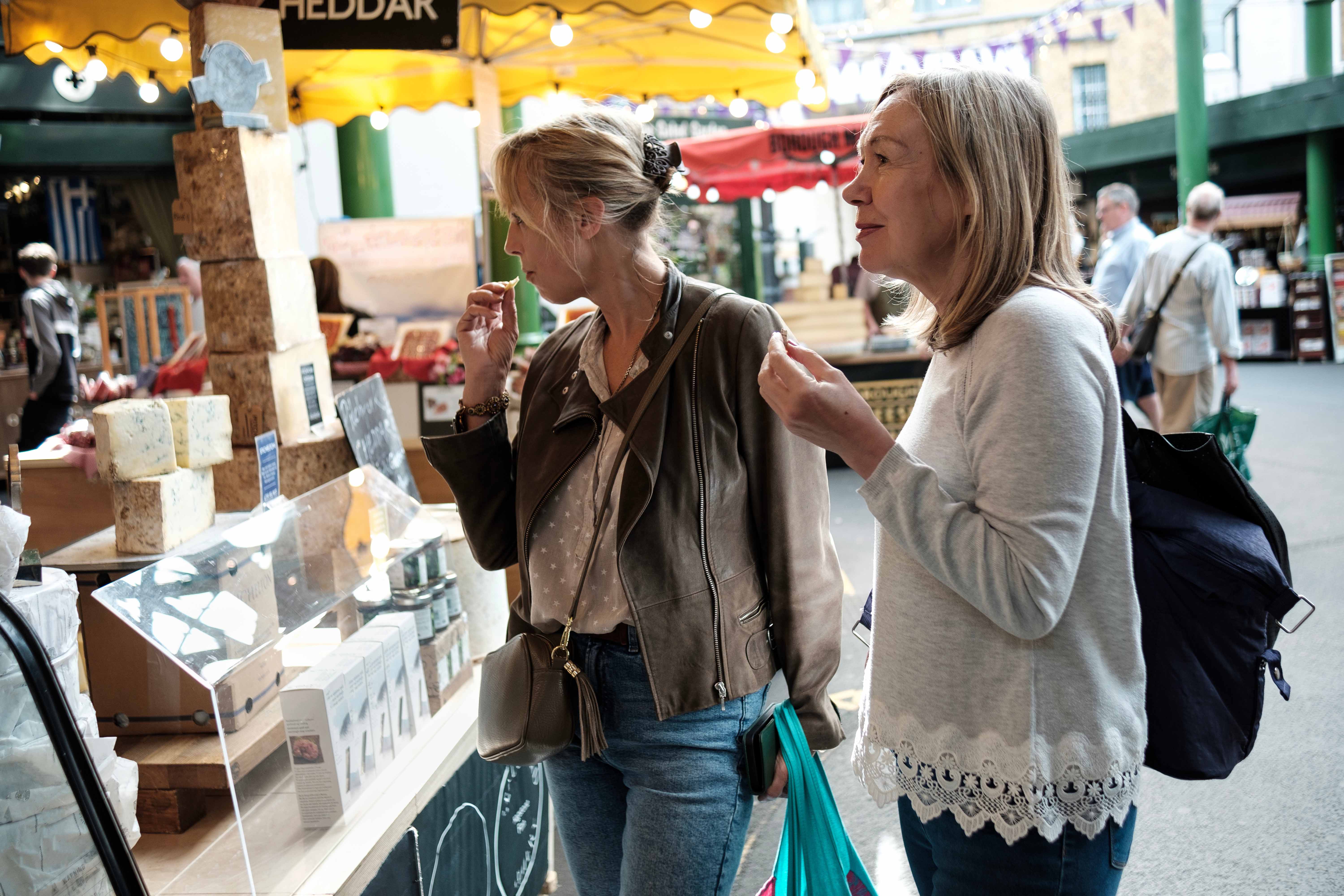 Visitors sampling cheese at a market stall during a London food tour.