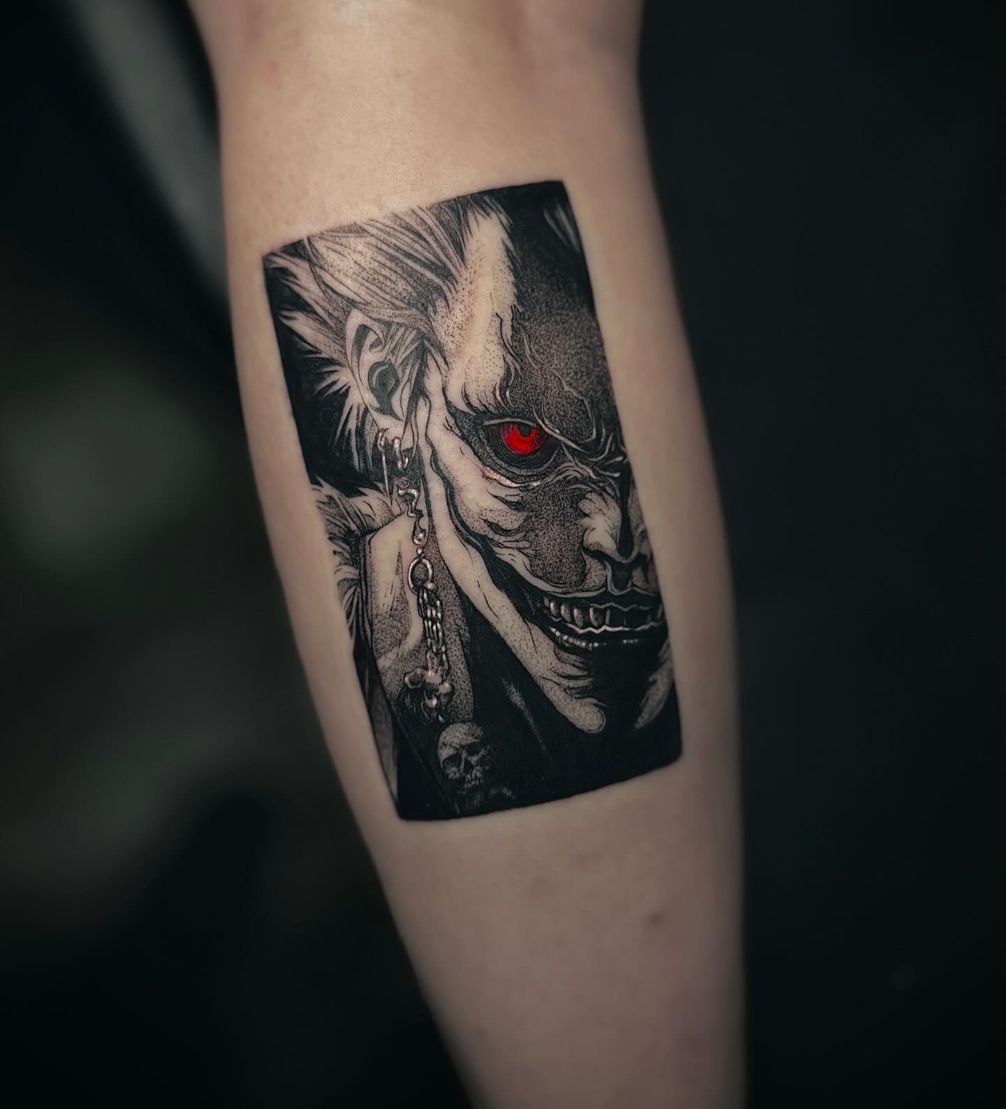 A grayscale anime-style tattoo of a character with spiky hair and a headband, holding a kunai.  The tattoo is on someone's forearm.