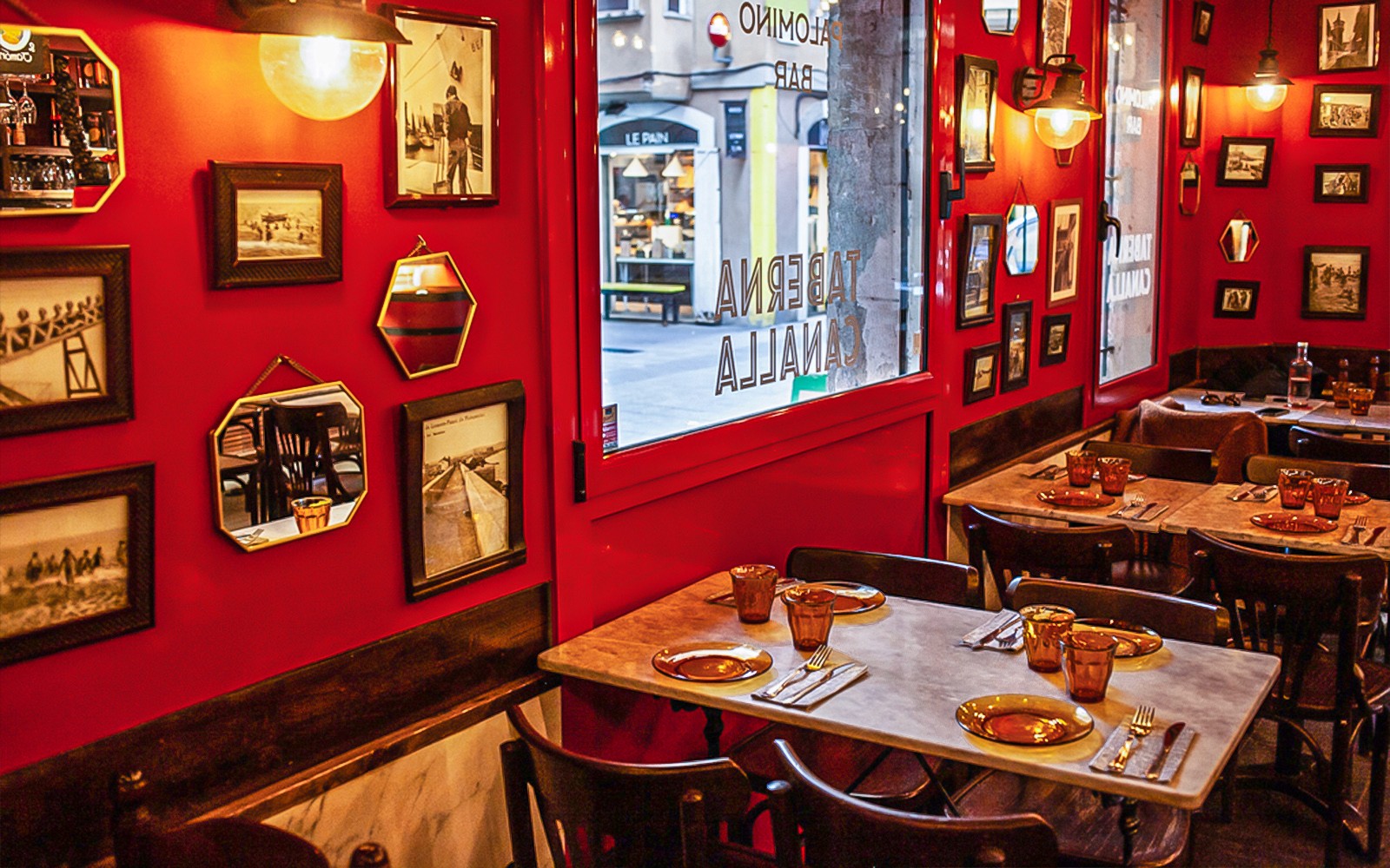 Hangulatos étterem belső tér La Barcelonetában, vörös falakkal és bekeretezett fotókkal, amely egy 3 órás, vezetett étel-túra része.