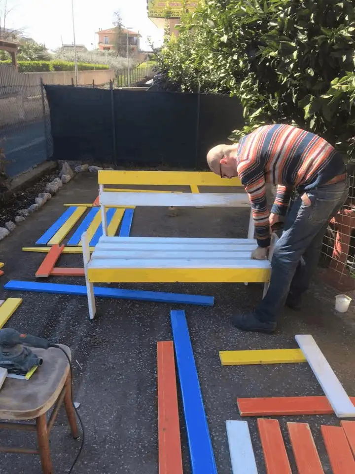 Carlo Celanetti mentre assembla delle panchine colorate nel laboratorio artigianale a Tivoli in uno spazio di lavoro organizzato in catena di montaggio seguendo il suo stile.