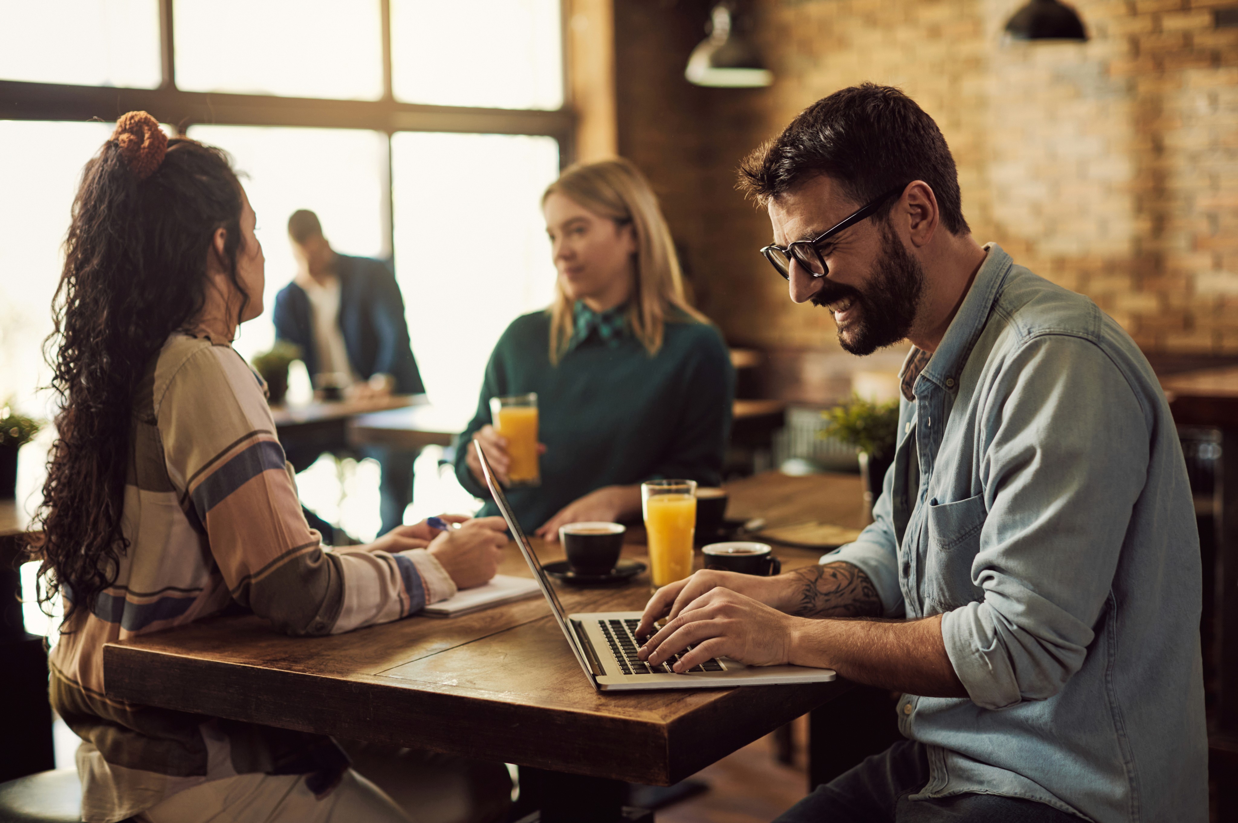 A group of colleagues having a productive meeting while working on a laptop at a café table.