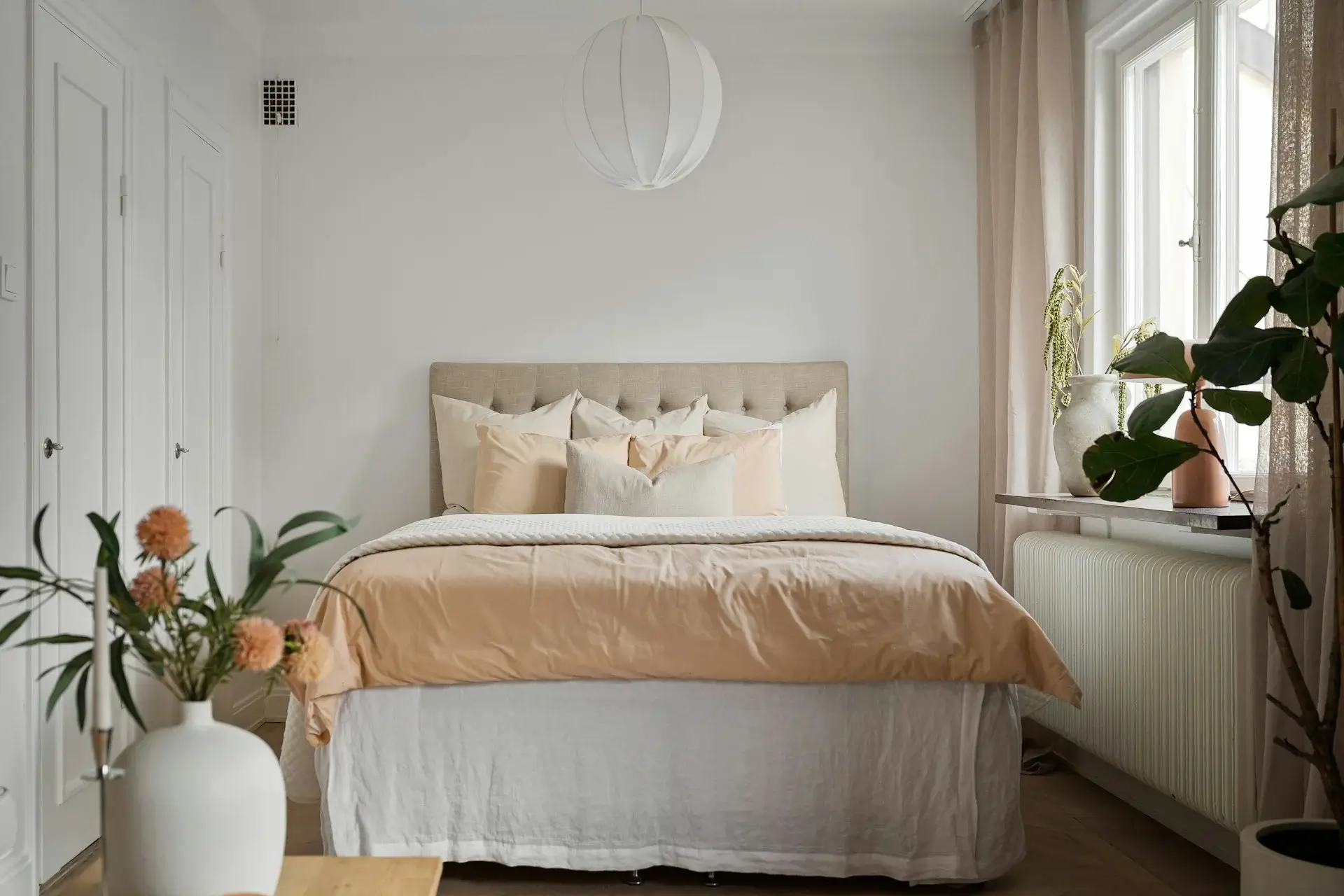 Minimal bedroom with beige bedding, soft pillows, and natural light.