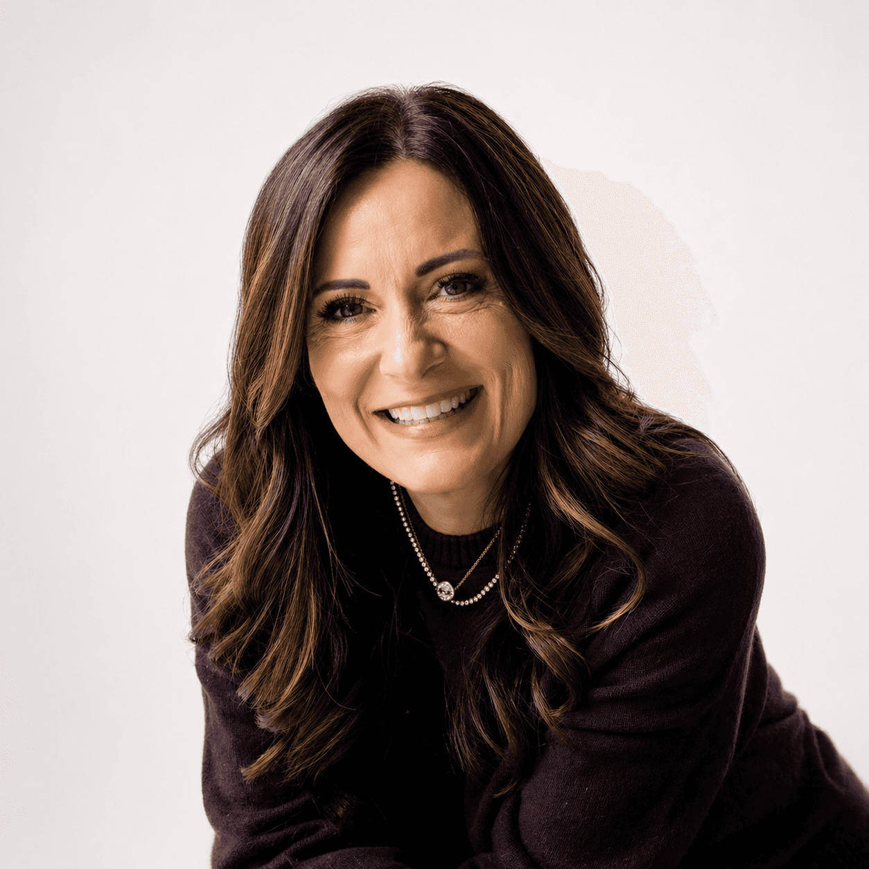 A man smiles and engages with two customers at a countertop in a modern cafe, with a honeycomb-patterned wall behind them.