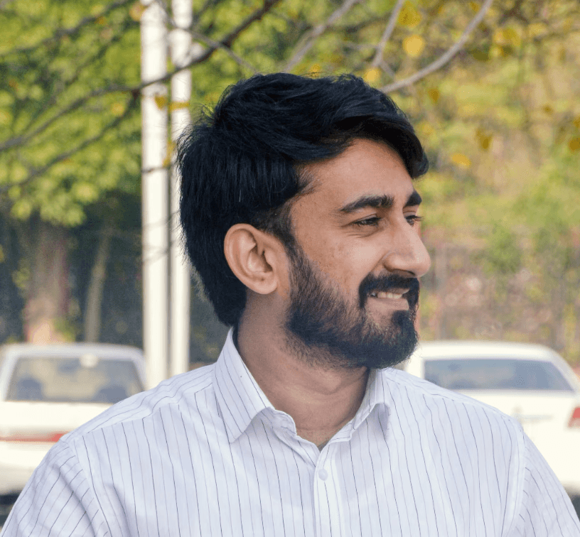 a young man wearing glasses standing in front of a mountain