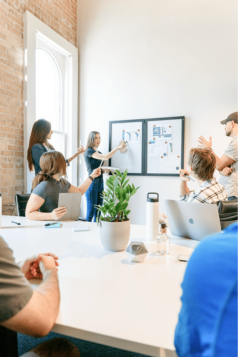 A woman in a white hoodie and sunglasses stands confidently, exuding a casual yet stylish vibe.