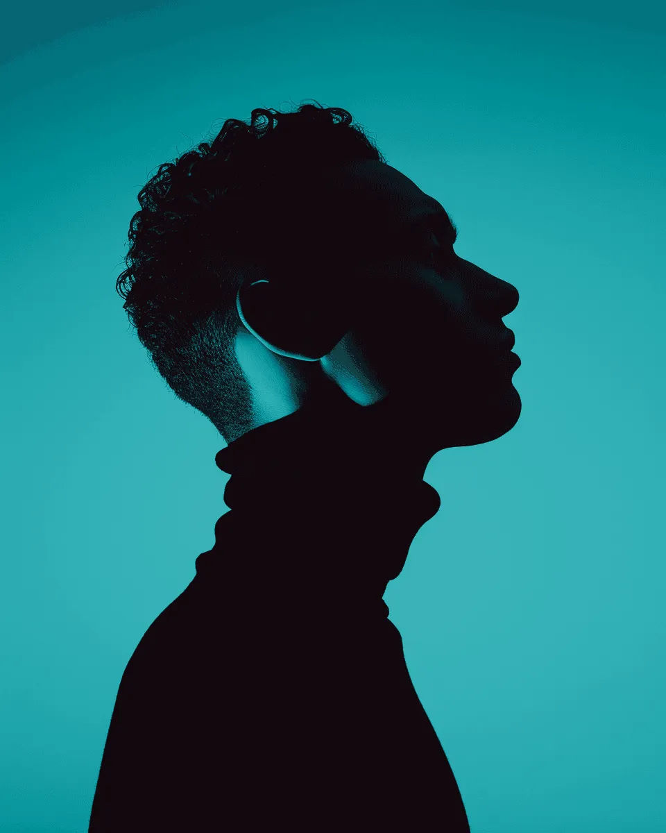 Silhouetted profile of a person in a turtleneck against a teal background. Soft lighting creates a dramatic and contemplative mood.