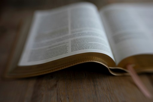 An open book with gold-gilded pages on a wooden surface.