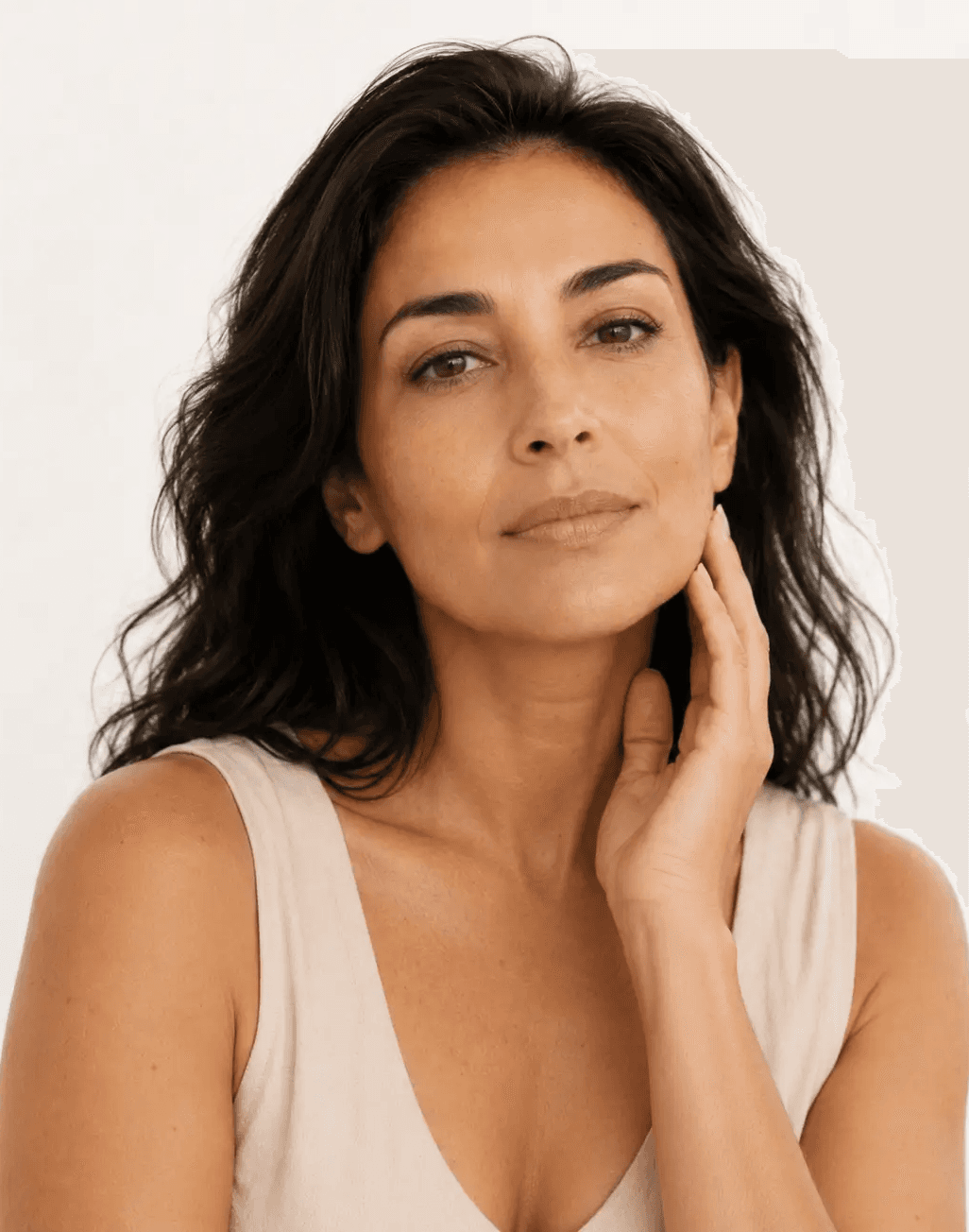 Mulher adulta de cabelos escuros com a mão próxima ao rosto e variações naturais de tonalidade na pele