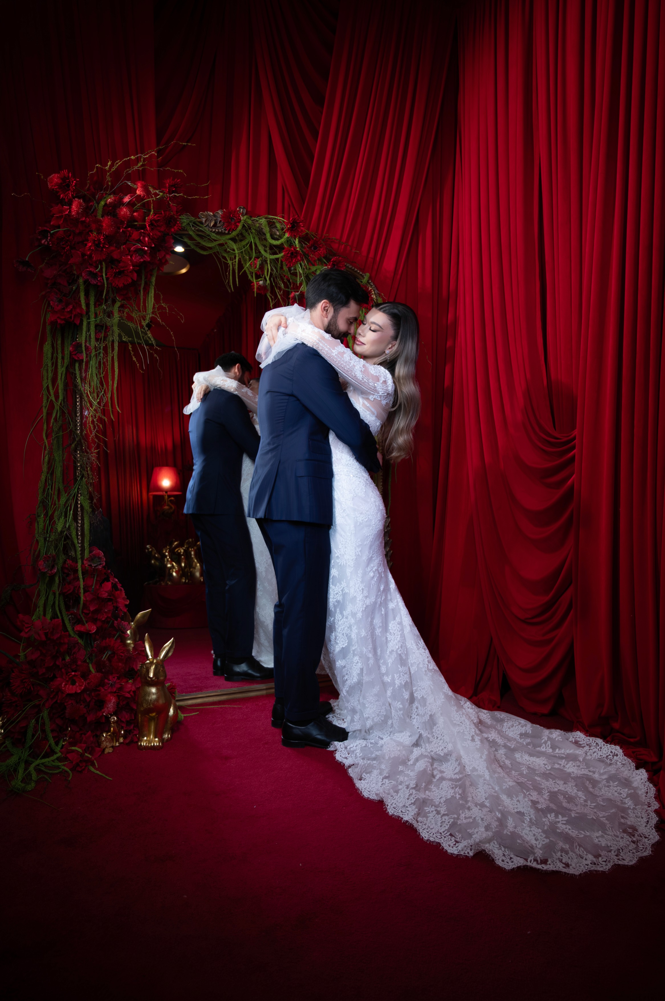 Mire și mireasă surprinși într-o îmbrățișare romantică într-un decor cu draperii roșii, ședință foto bridal în București