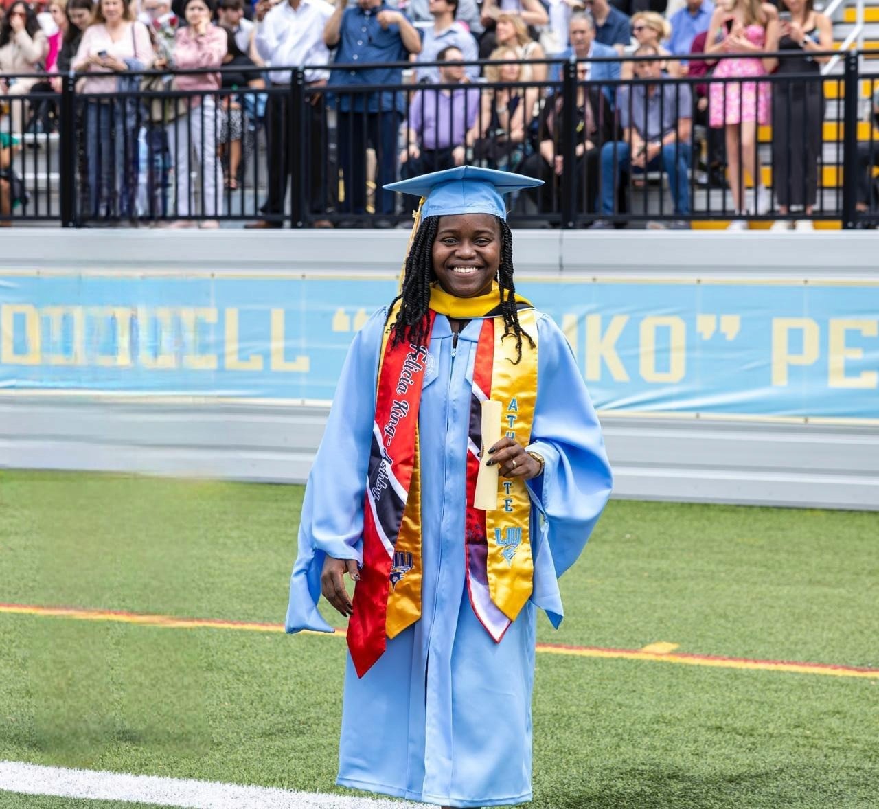 Graduate Felicia King smiles in cap and gown at university ceremony, symbolizing triumph and empowerment through mentorship and education.