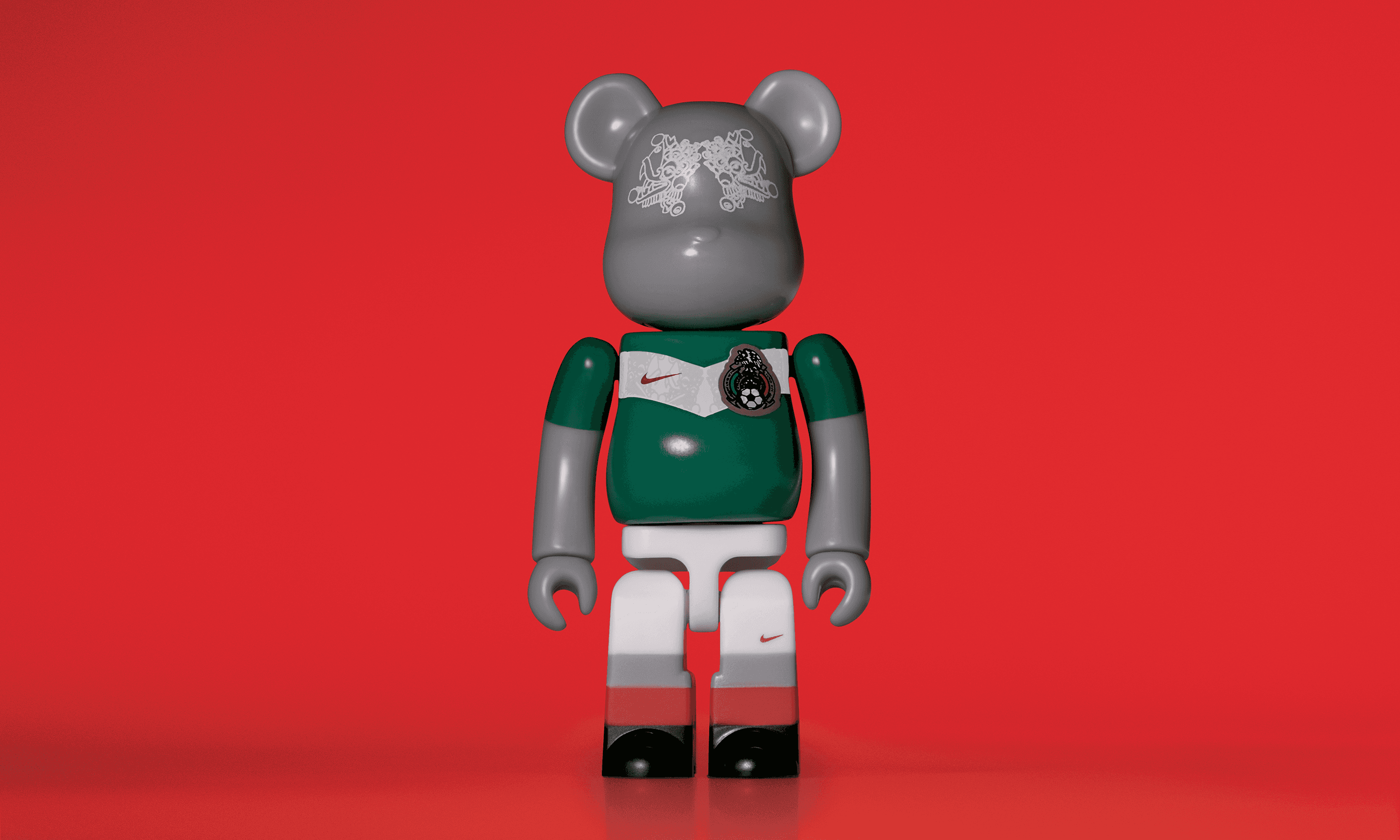 A single 3.5” tall Bre@rbrick/Nike toy created to commemorate the 2006 Mexican World Cup football team. The toy is painted to appear in the Mexican football kit and stands in the center of the frame in front of a red background. 