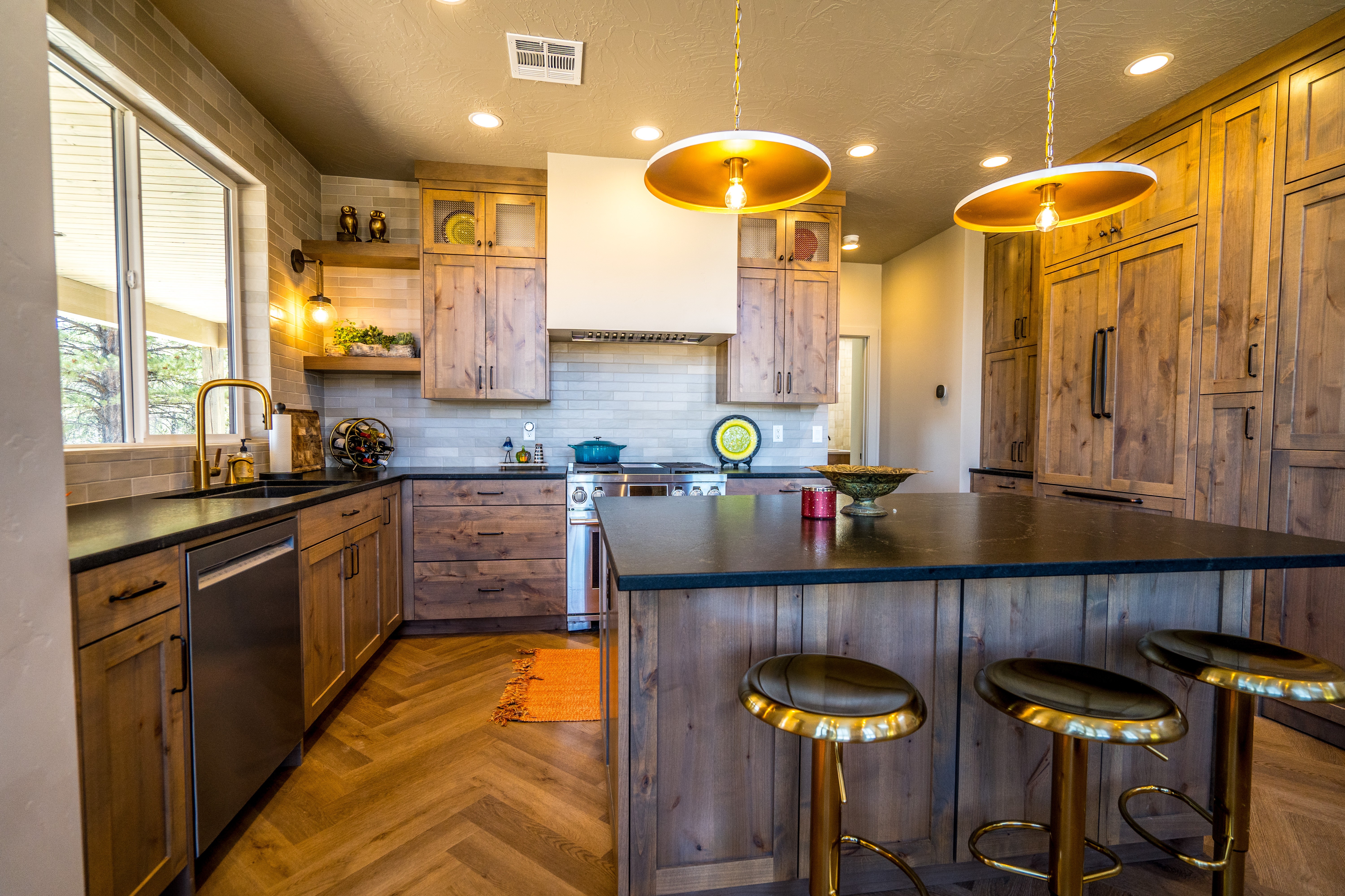 Modern kitchen in a custom home in Orderville, Utah with painted cabinetry and wood tone flat panel cabinetry, custom light fixtures, and an open concept living space.