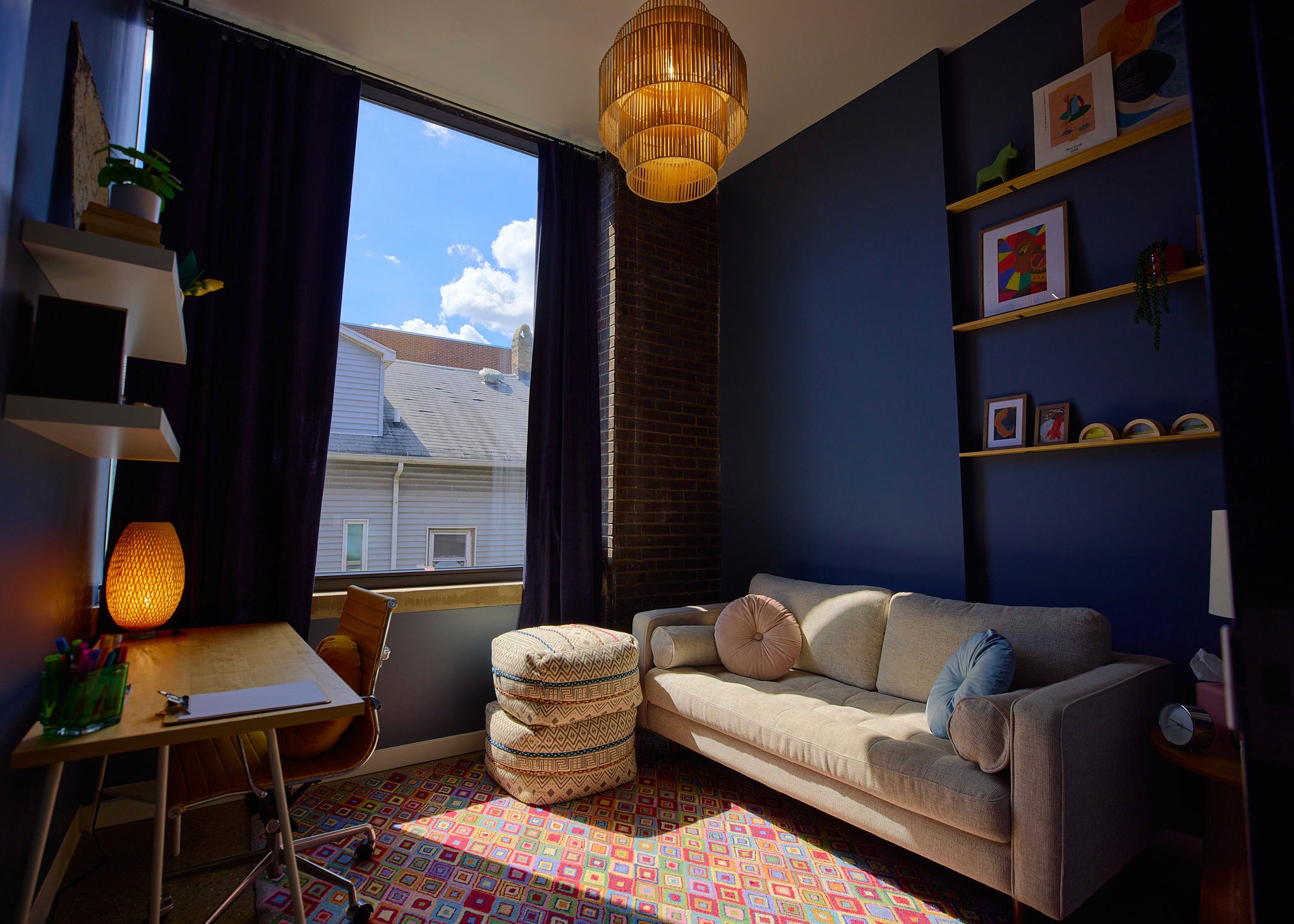 A crow perched on a pipe against an orange sky.