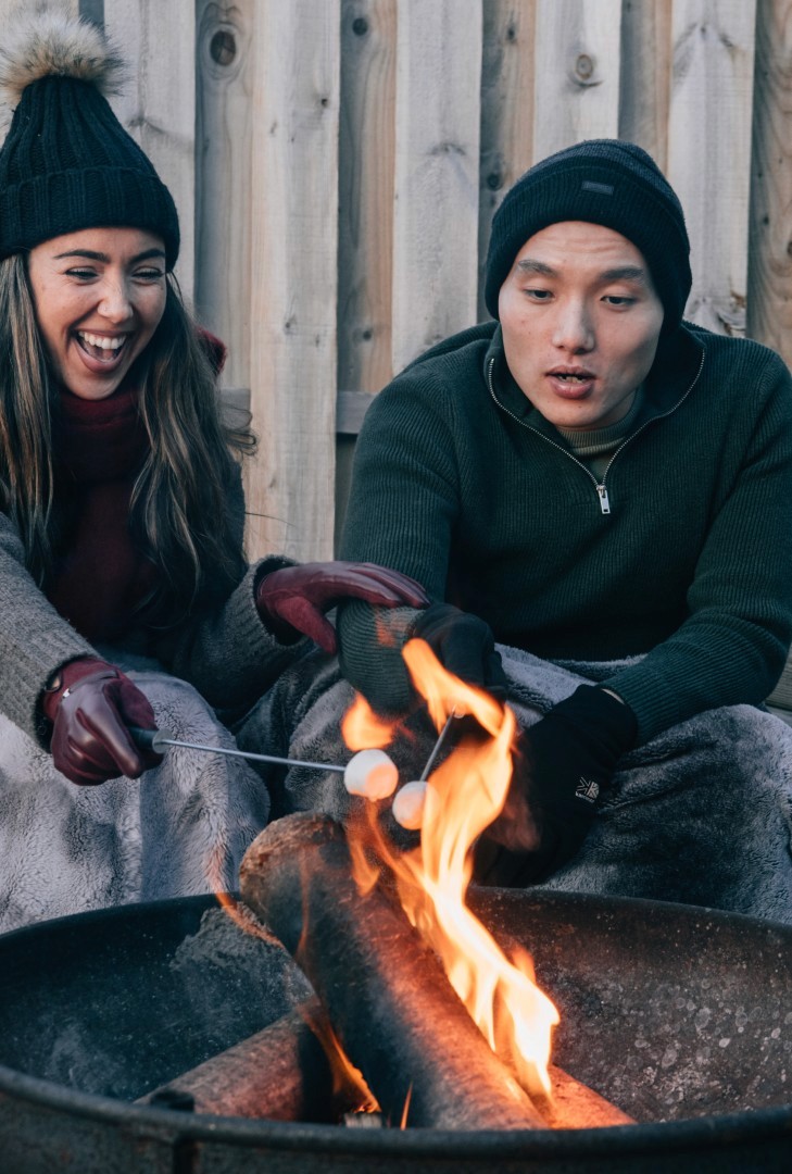 A couple sitting around a firepit roasting marshmellows.