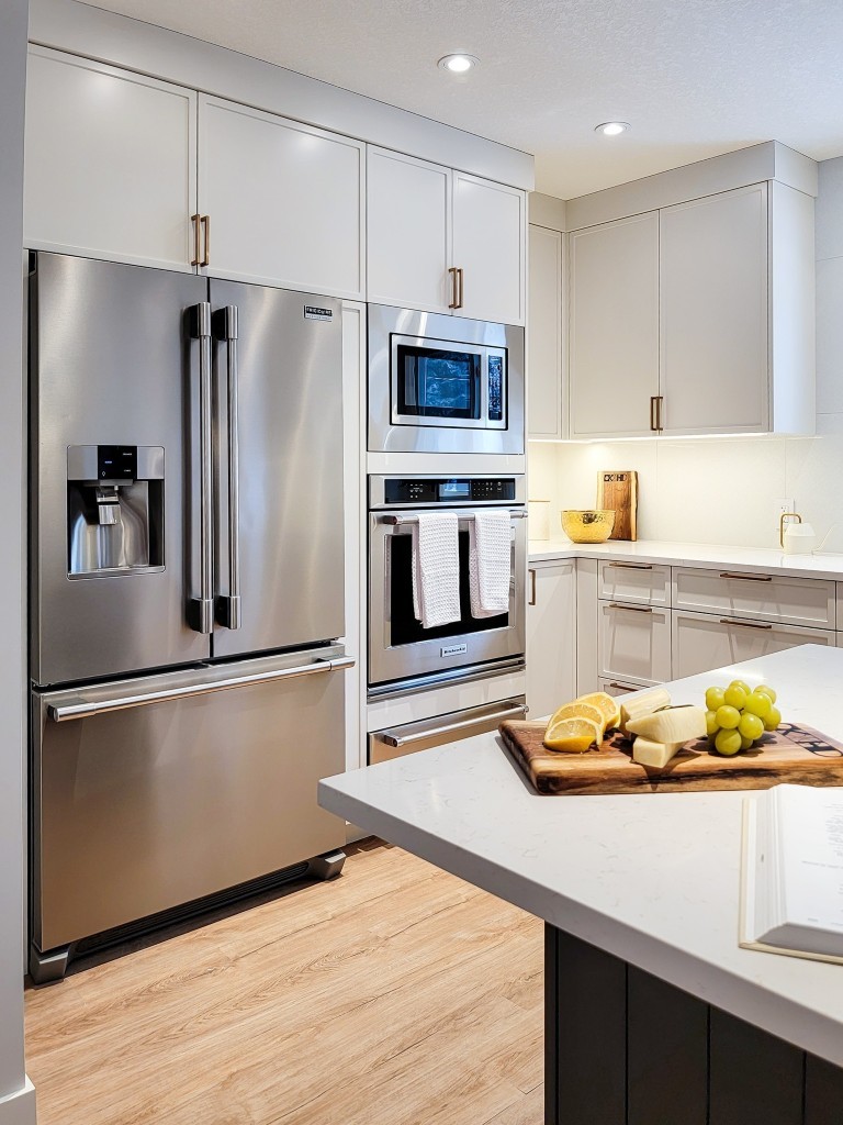 Image of Modern kitchen with stainless steel appliances, white cabinets, and island featuring marble countertop and fresh fruit.