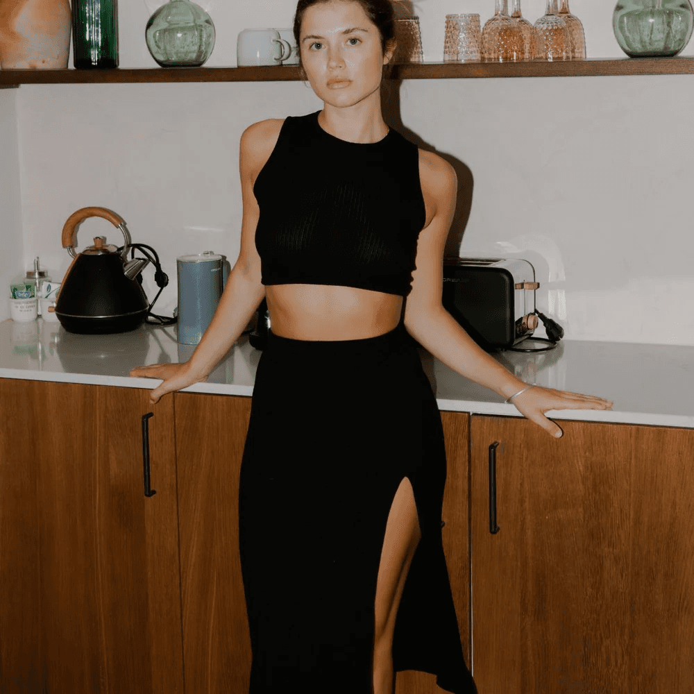 Woman in black workout attire standing in kitchen with kettle and toaster on countertops behind her.