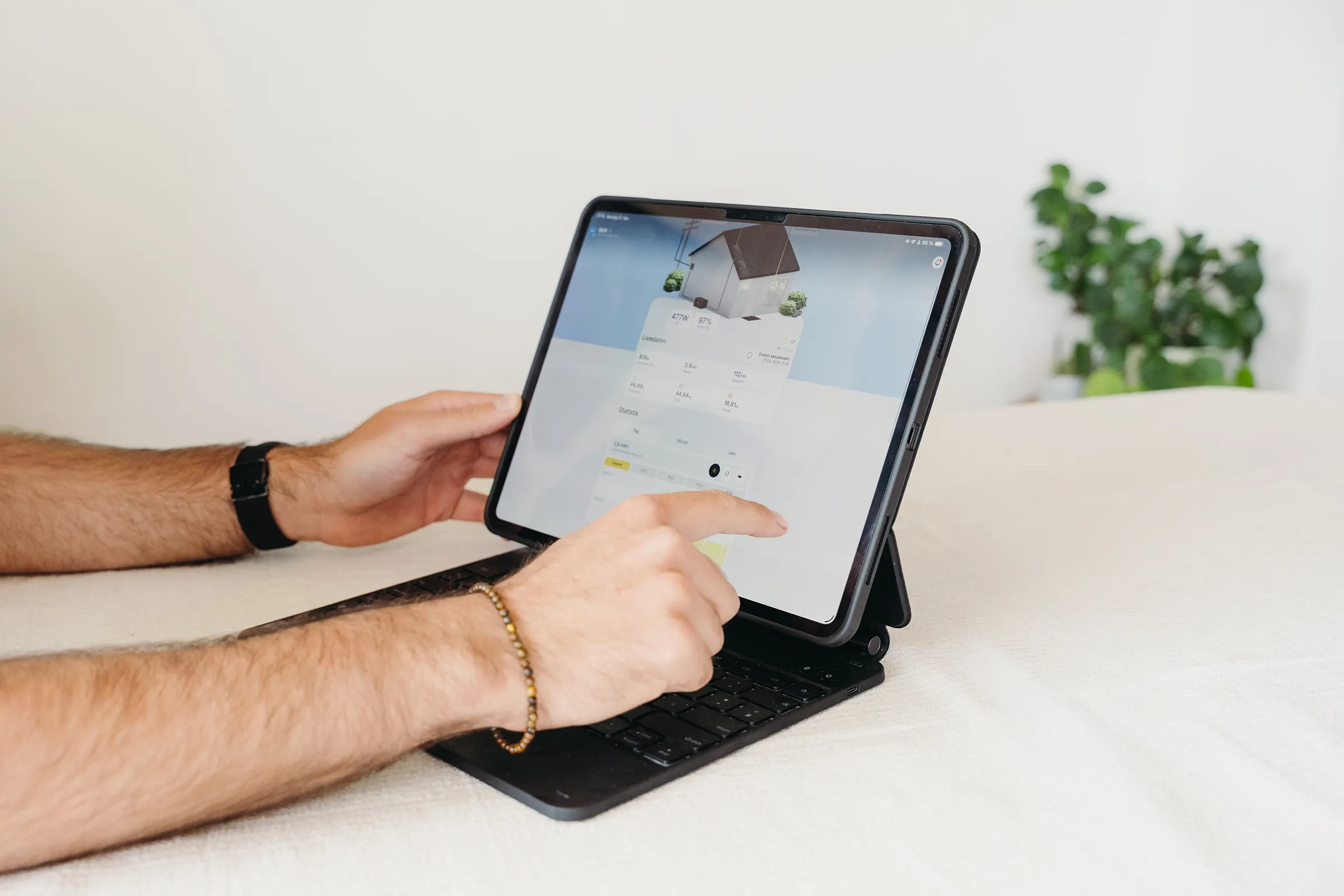 Energieberater analysiert Energiedaten einer Photovoltaikanlage und eines Wohngebäudes auf einem Tablet.