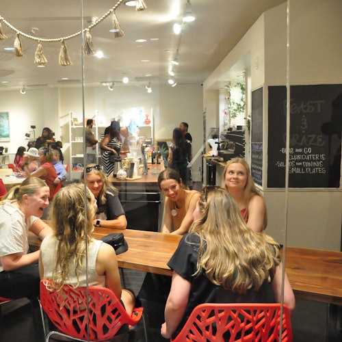 Výhled na kavárnu přes skleněné panely a stůl přátel, kteří si užívají společnou chvíli