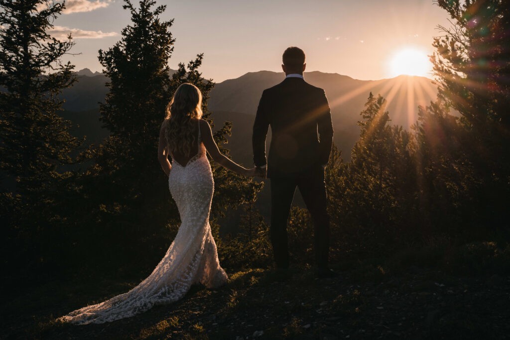 Newlywed couple standing together and looking out over a wilderness landscape.