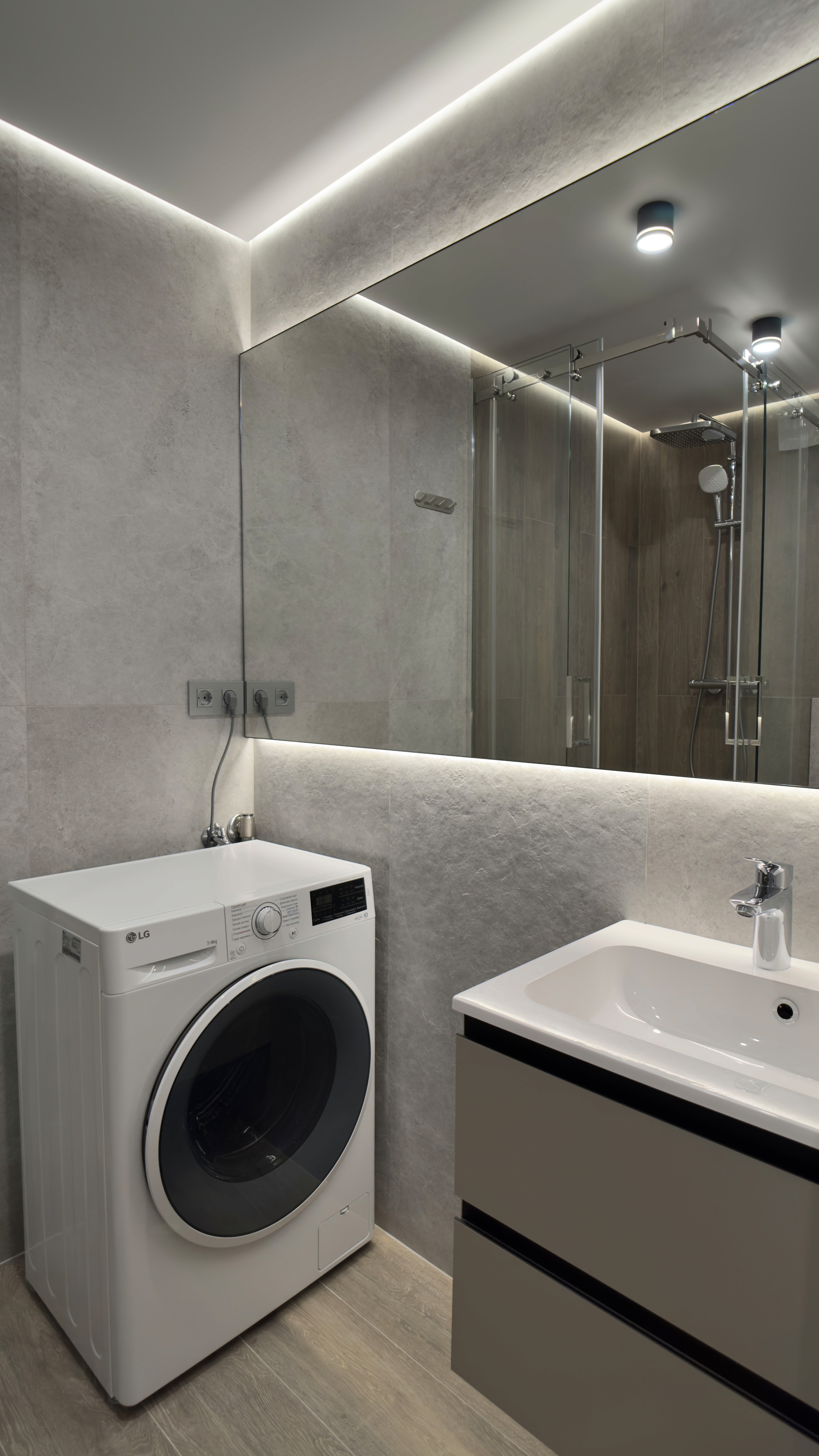 Сучасна ванна кімната з пральною машиною, дзеркалом з підсвічуванням і душовою